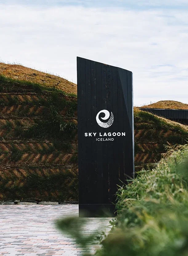 Entrance sign for Sky Lagoon in Iceland, with a black background and white logo.