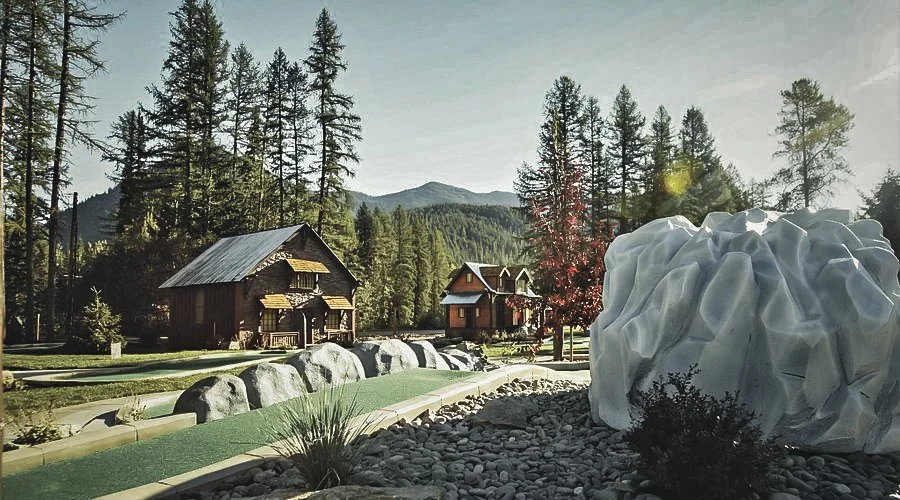 A miniature model of a mountain landscape with houses, trees, rocks, and a large white rock formation in the foreground.