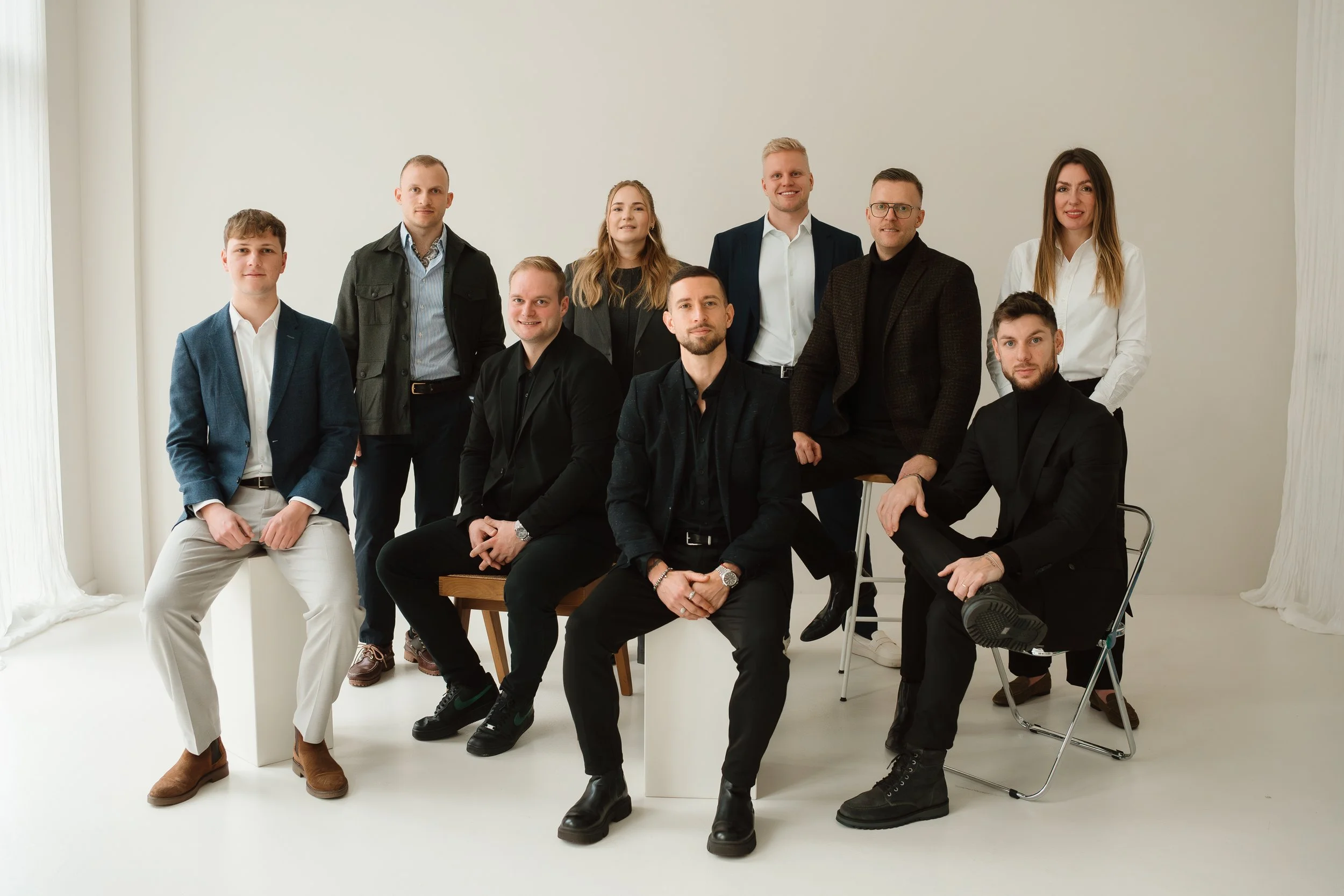 Teamfoto vor hellem Hintergrund. Es sind elf Personen zu sehen. Sowohl Männer als auch Frauen  Einige stehen, einige sitzen.