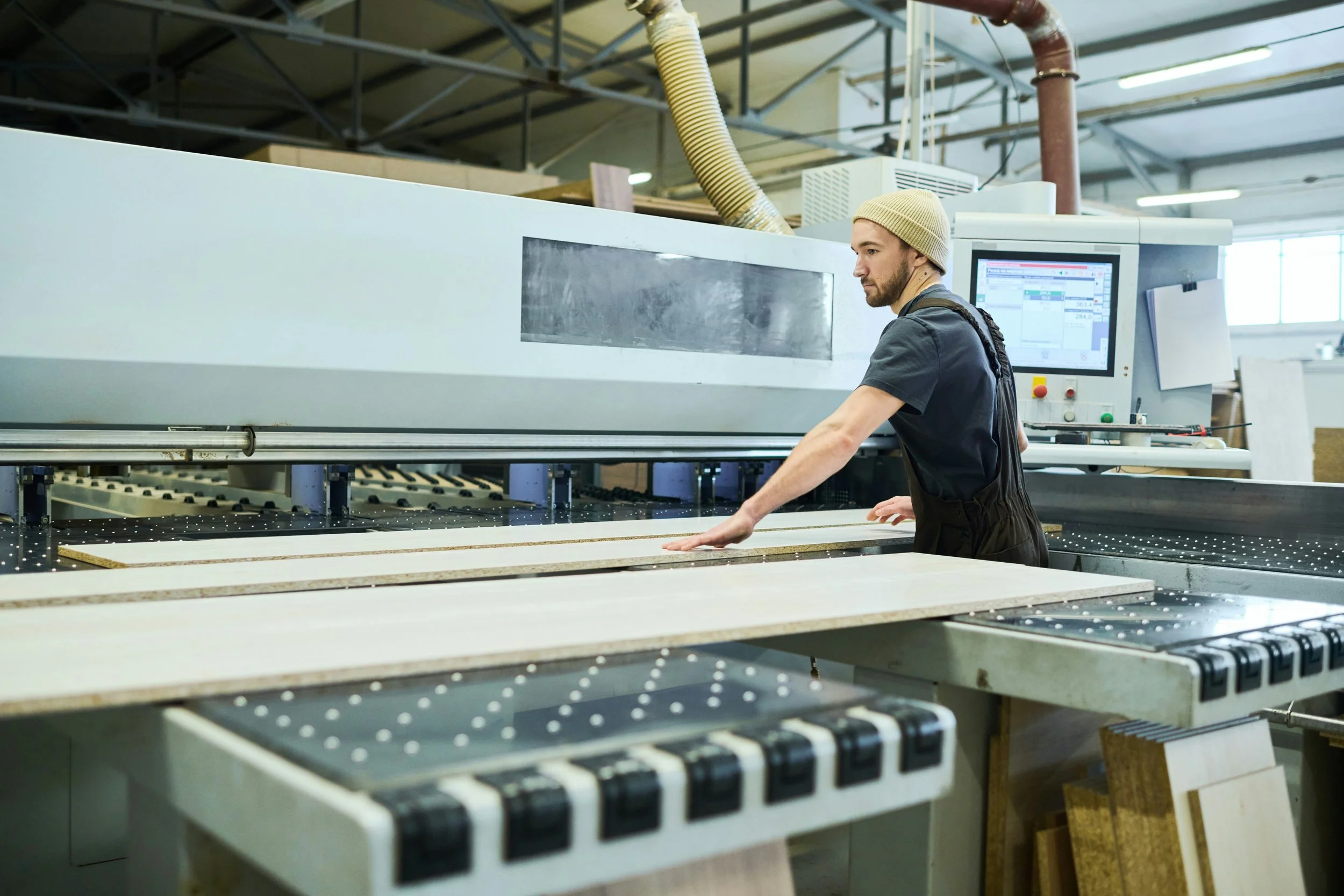 Mann arbeitet in einer Holzverarbeitungsfabrik bei einer großen CNC-Maschine.