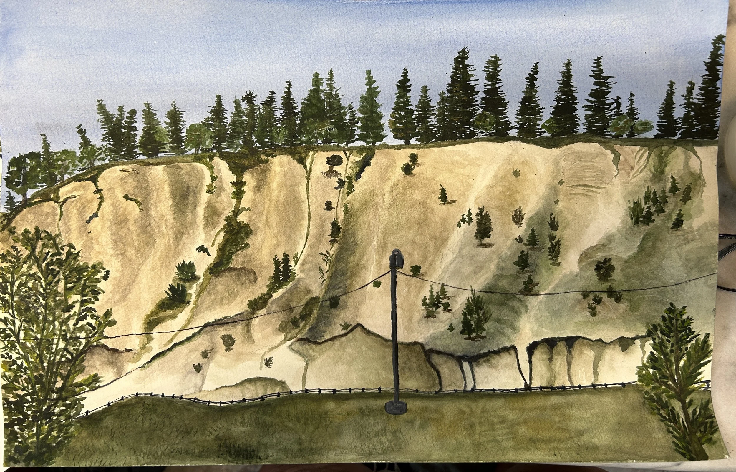Watercolor painting of a dirt cliff with greenery and trees on top, trees on the slope, and a grassy area with a fence and a streetlamp in the foreground.