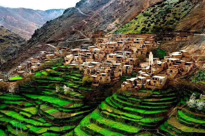 Wide Atlas Mountain landscape with a traditional Berber village, warm earth tones, and dramatic peaks.