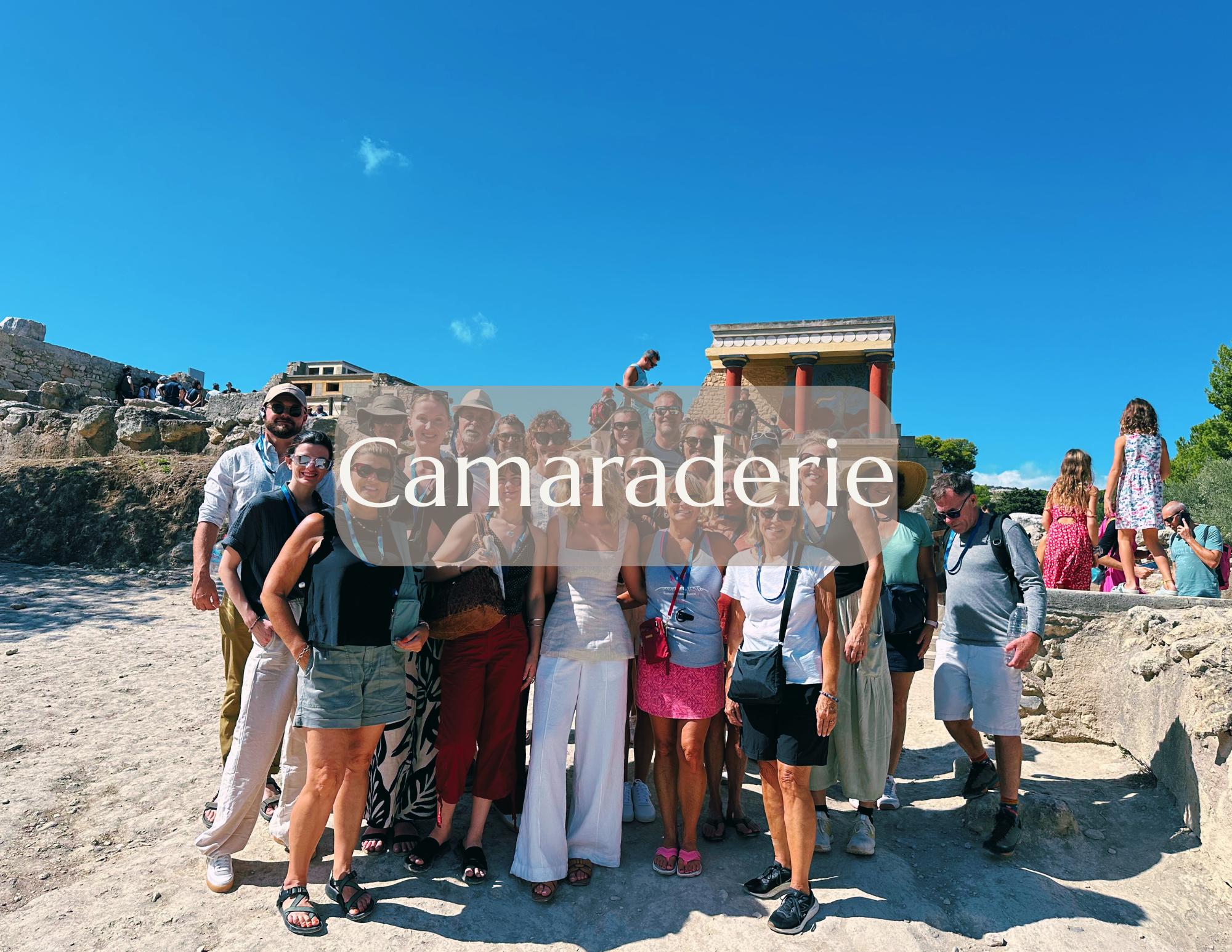 Group of people sightseeing at archaeological site with ruins and columns under a clear blue sky, some taking photos and others standing or walking.