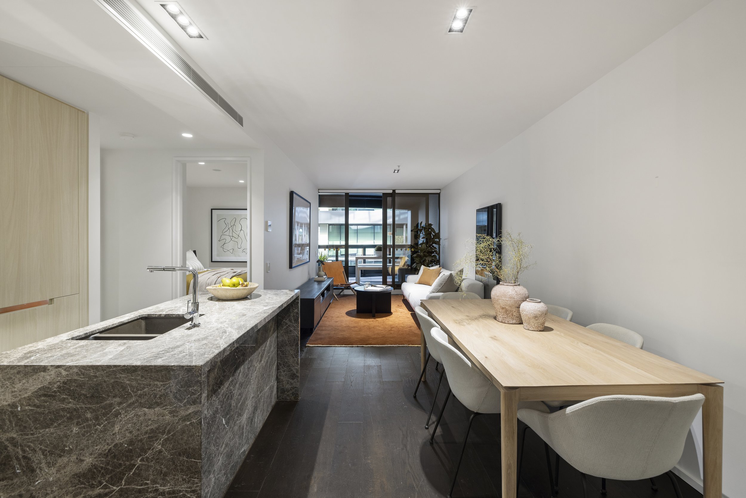 Modern open-concept apartment with kitchen, dining, and living areas, large window with balcony, minimal decor, and neutral color palette.