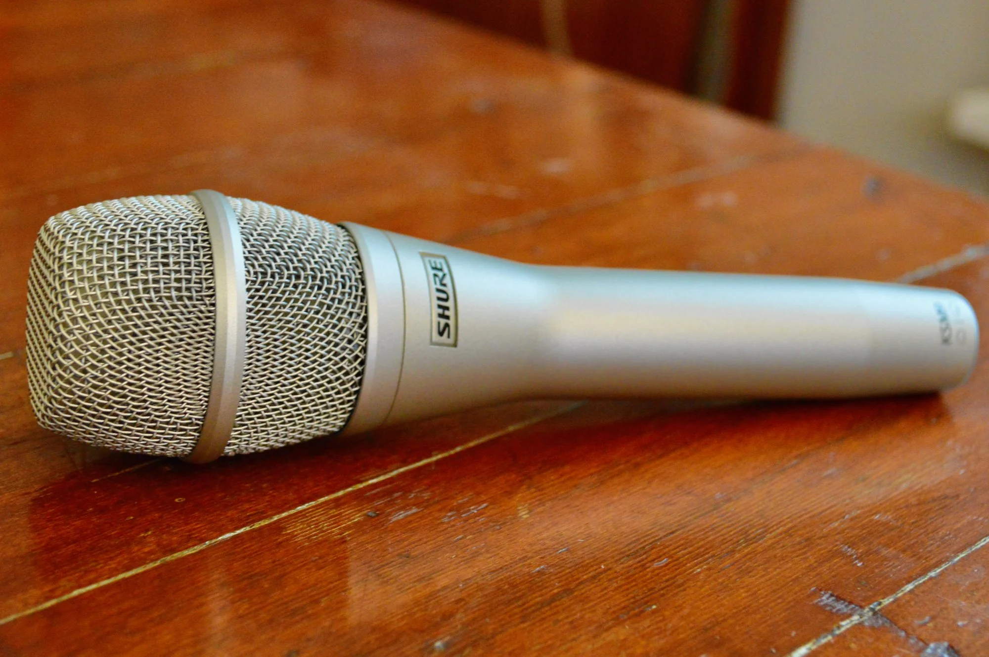 A silver Shure microphone resting on a wooden surface.