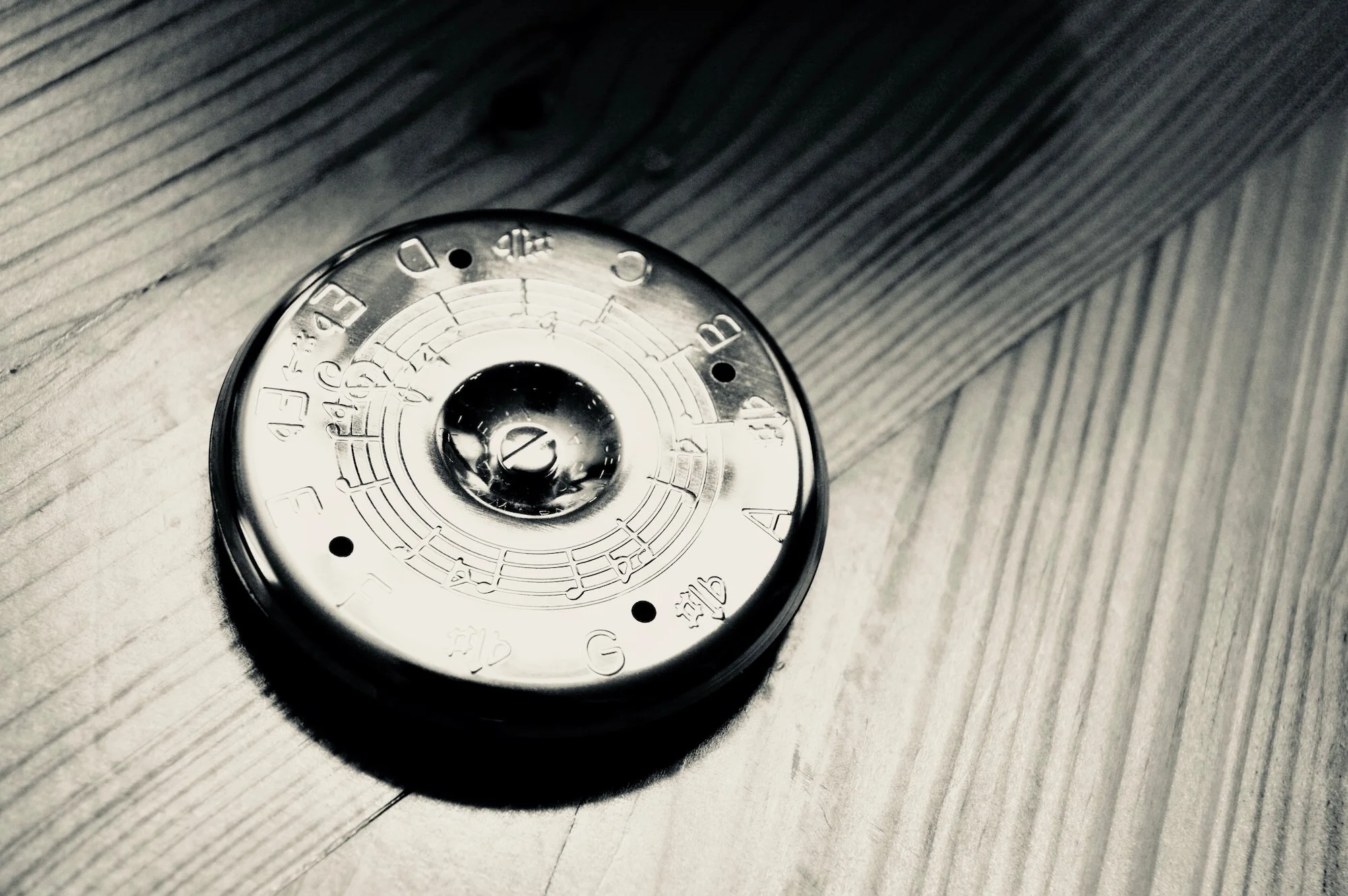 Pitch pipe on a wooden surface, depicted in black and white.