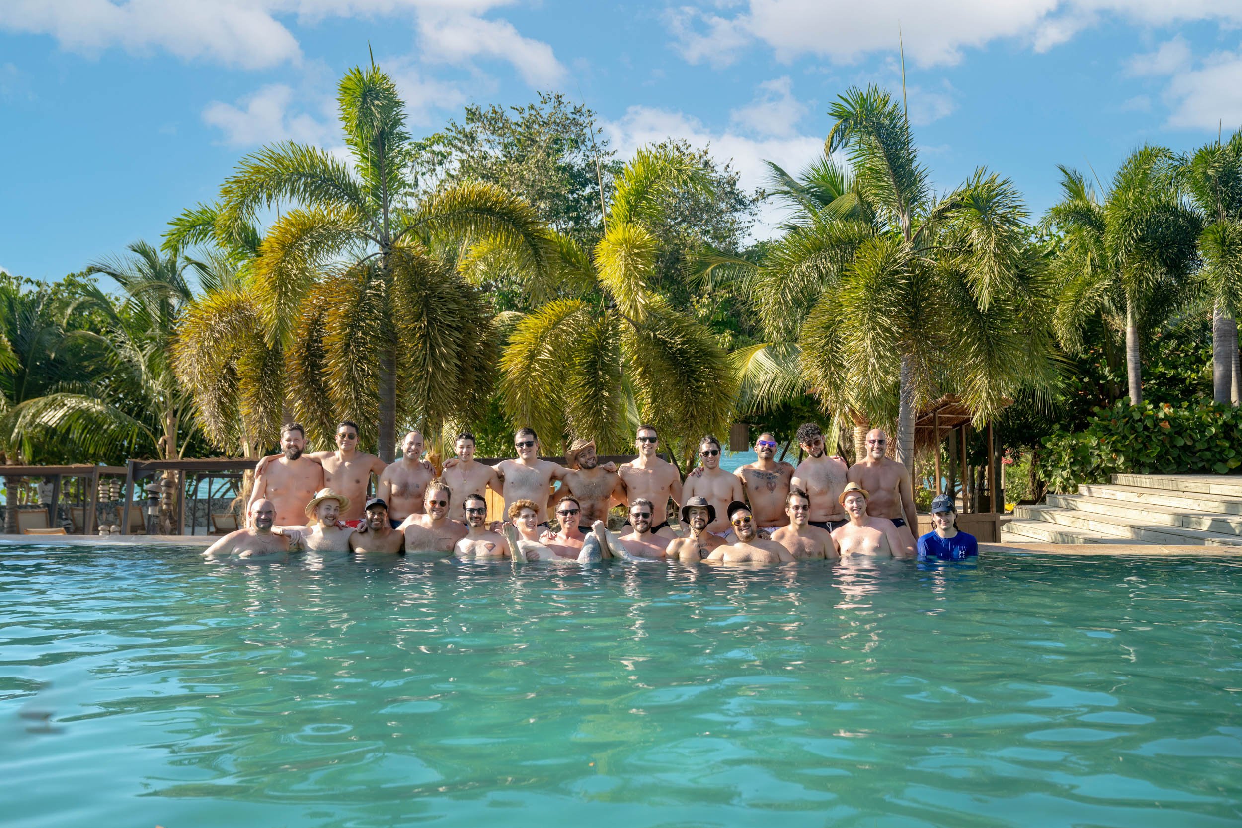 LGBTQ+ travel group posing together in a tropical resort pool in Cartagena, Colombia.