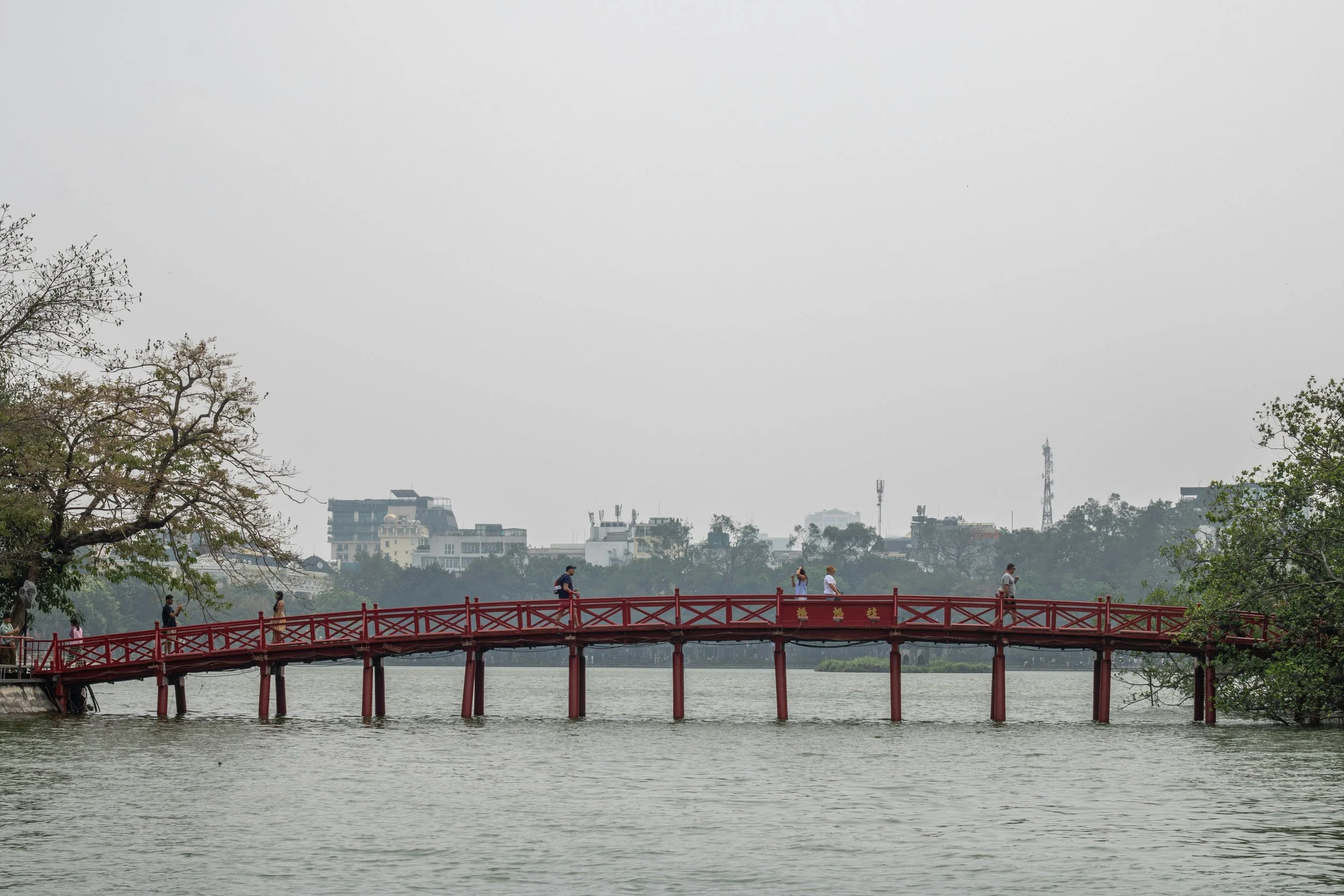 Red wooden bridge crossing Hoan Kiem Lake in Hanoi.