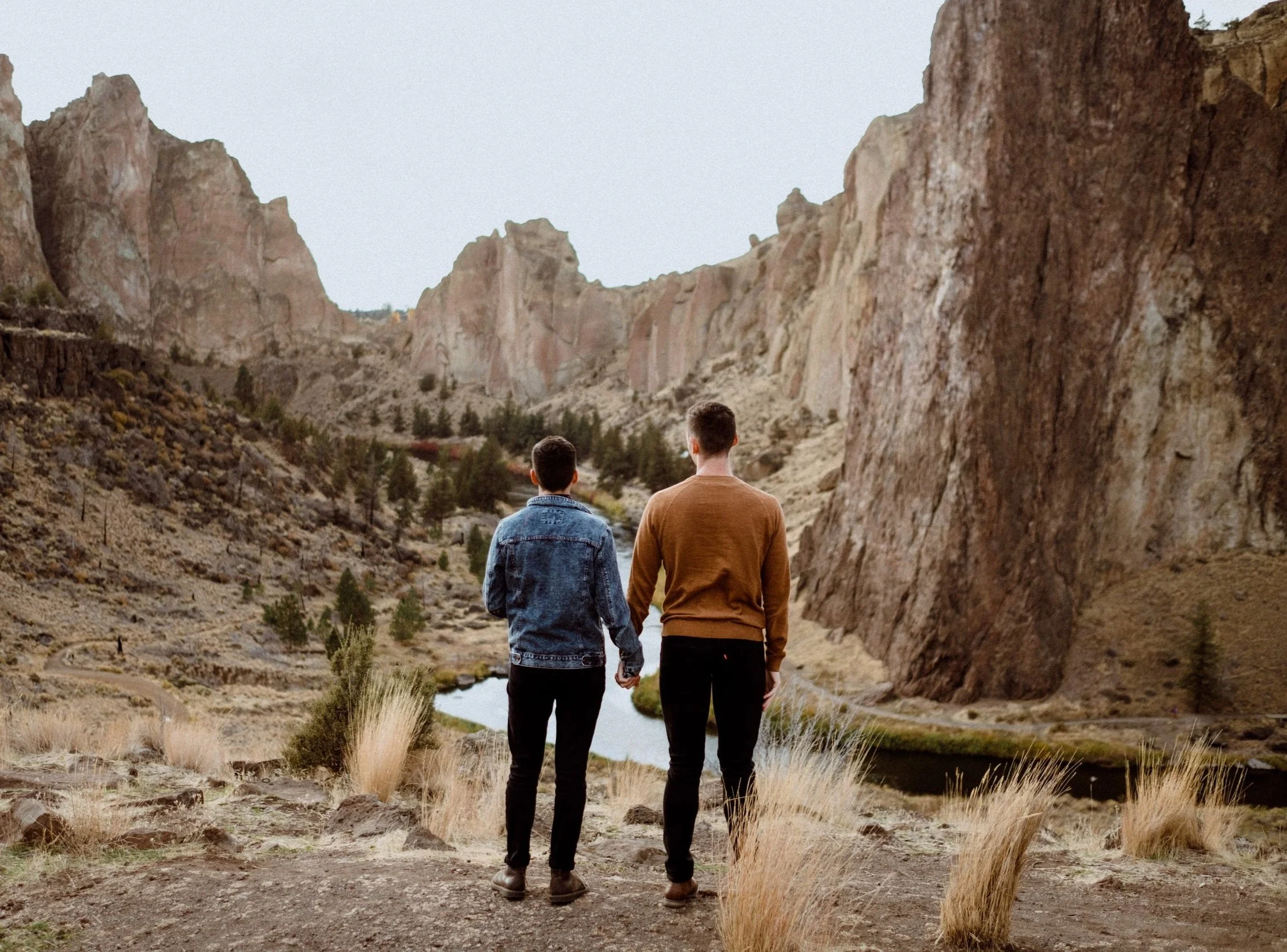 gay couple holding hands in front of a rock formation