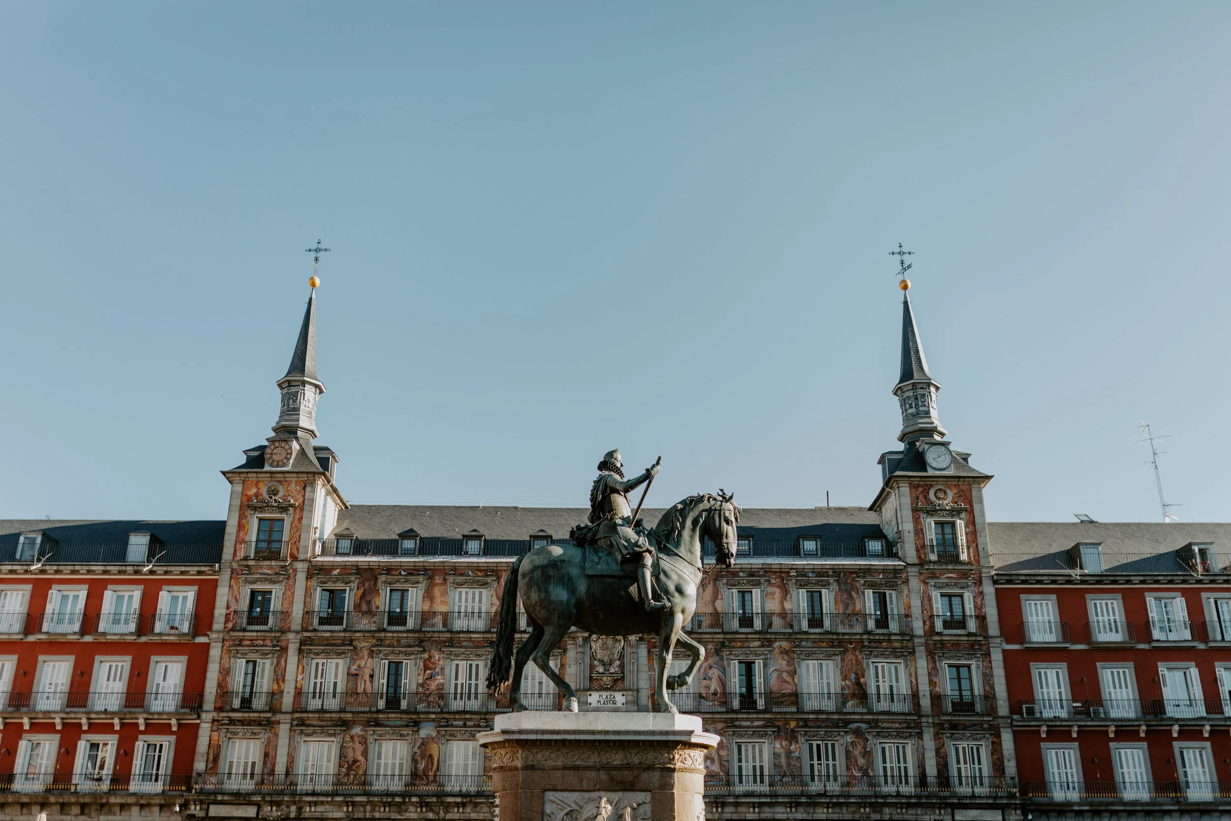 King Philips III’s bronze statue is set in the center of Plaza Mayor. Surrounding, a lively square of vendors, tourists, locals passing through and waiters tending to their tables.