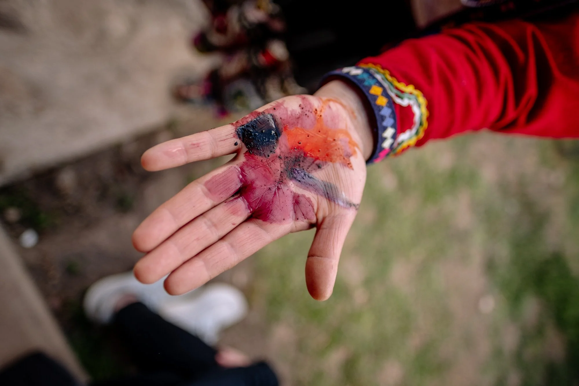 Hand covered in vibrant natural dyes during a textile workshop in the Sacred Valley, Peru.