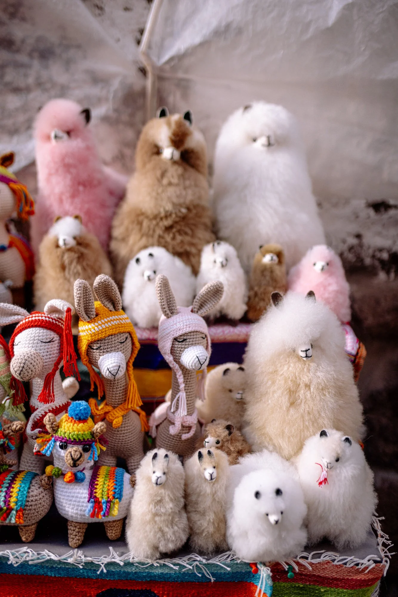 Colorful handmade alpaca wool stuffed animals and crocheted llamas at a Cusco artisan market, Peru.