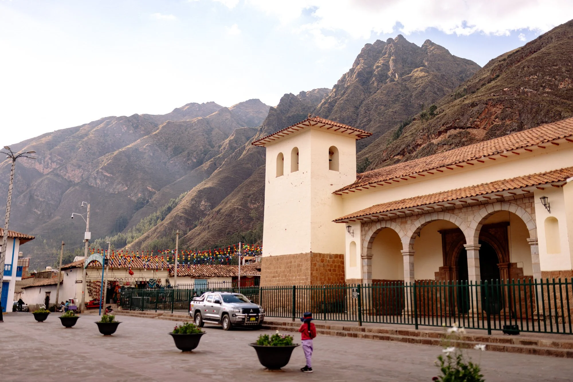 Colonial church with bell tower on a mountain-backed plaza in Peru's Sacred Valley.