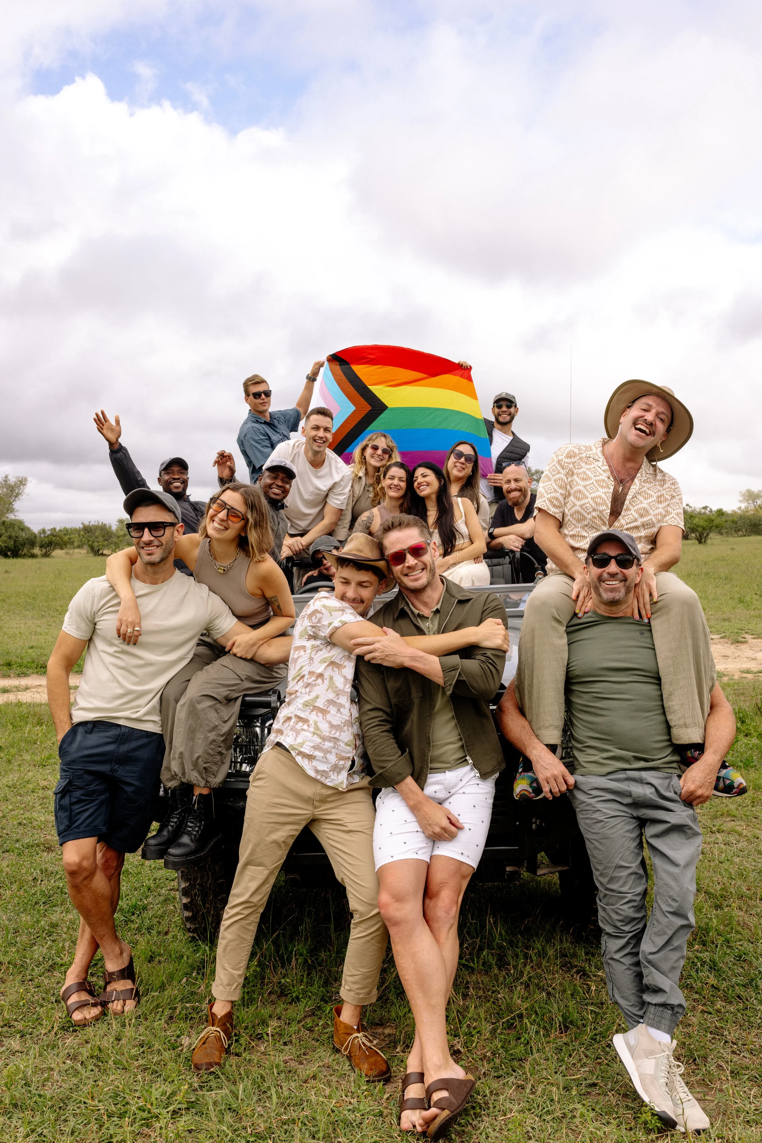 Group of LGBTQ+ travelers taking a photo with a pride flag on Silvan Safari in South Africa. Small-group adventure.