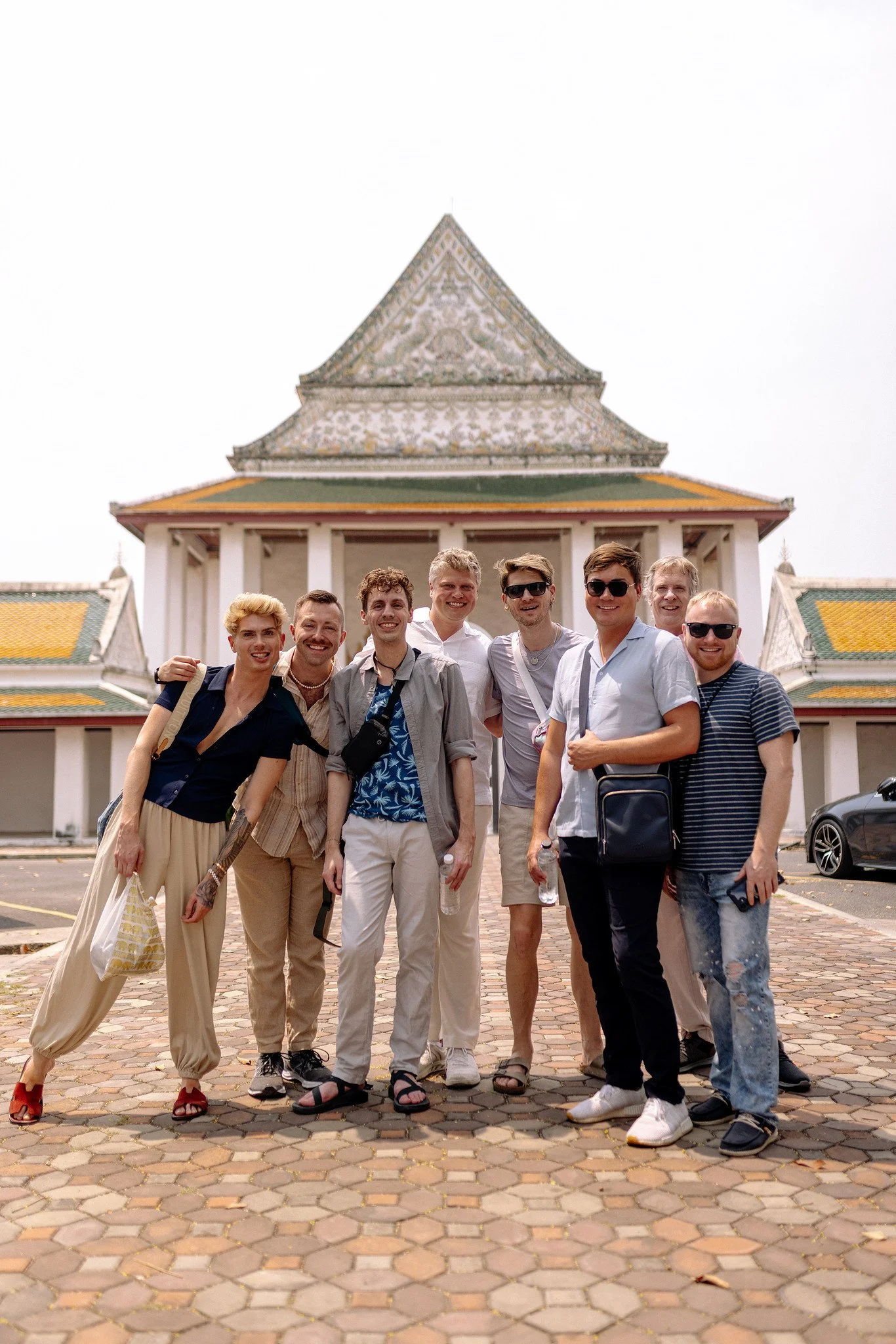  Friends from a SideQuests Thailand trip gather in front of a green-roofed pavilion at the Grand Palace 