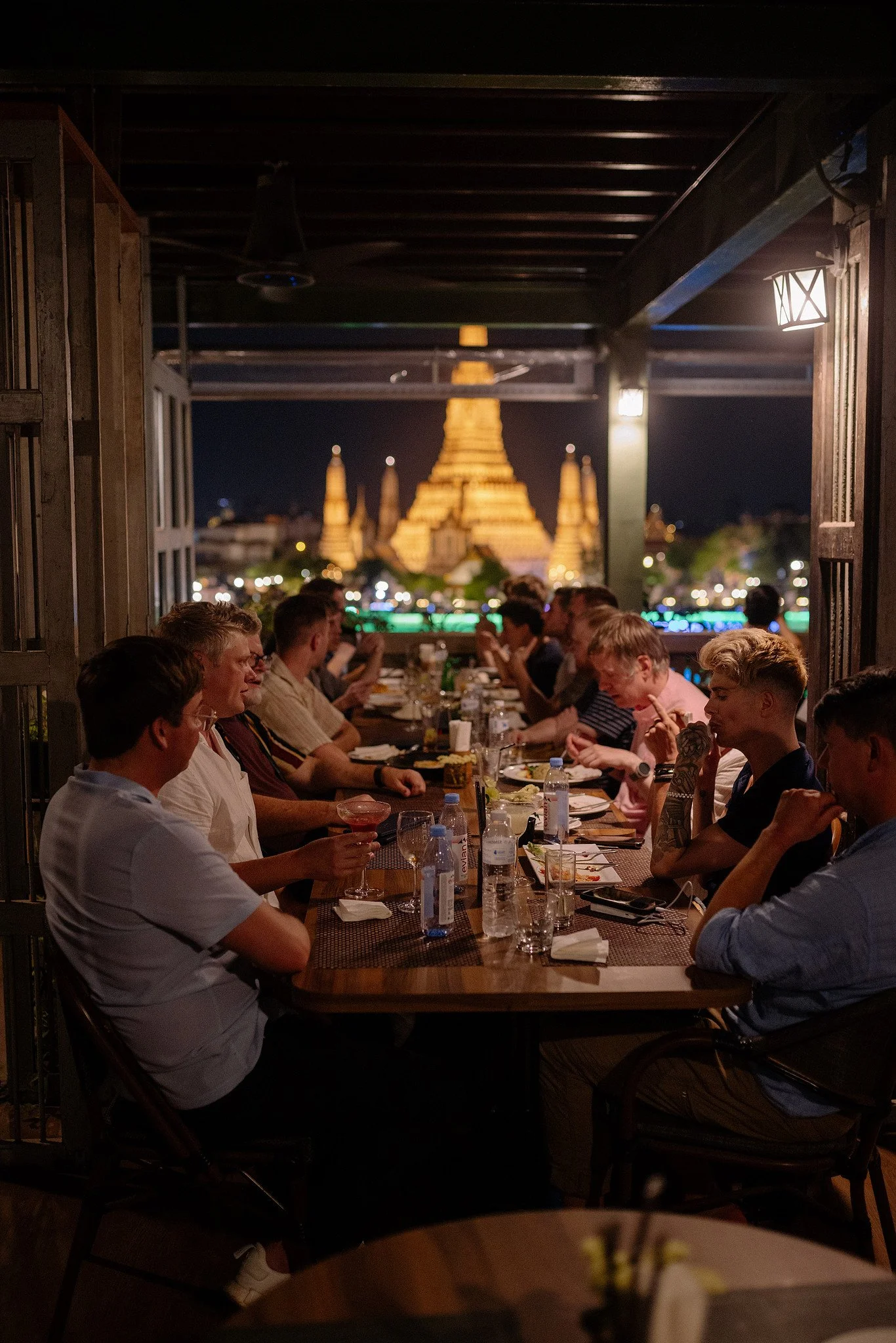  Dinner on a rooftop terrace with Bangkok's illuminated Wat Arun in the background 