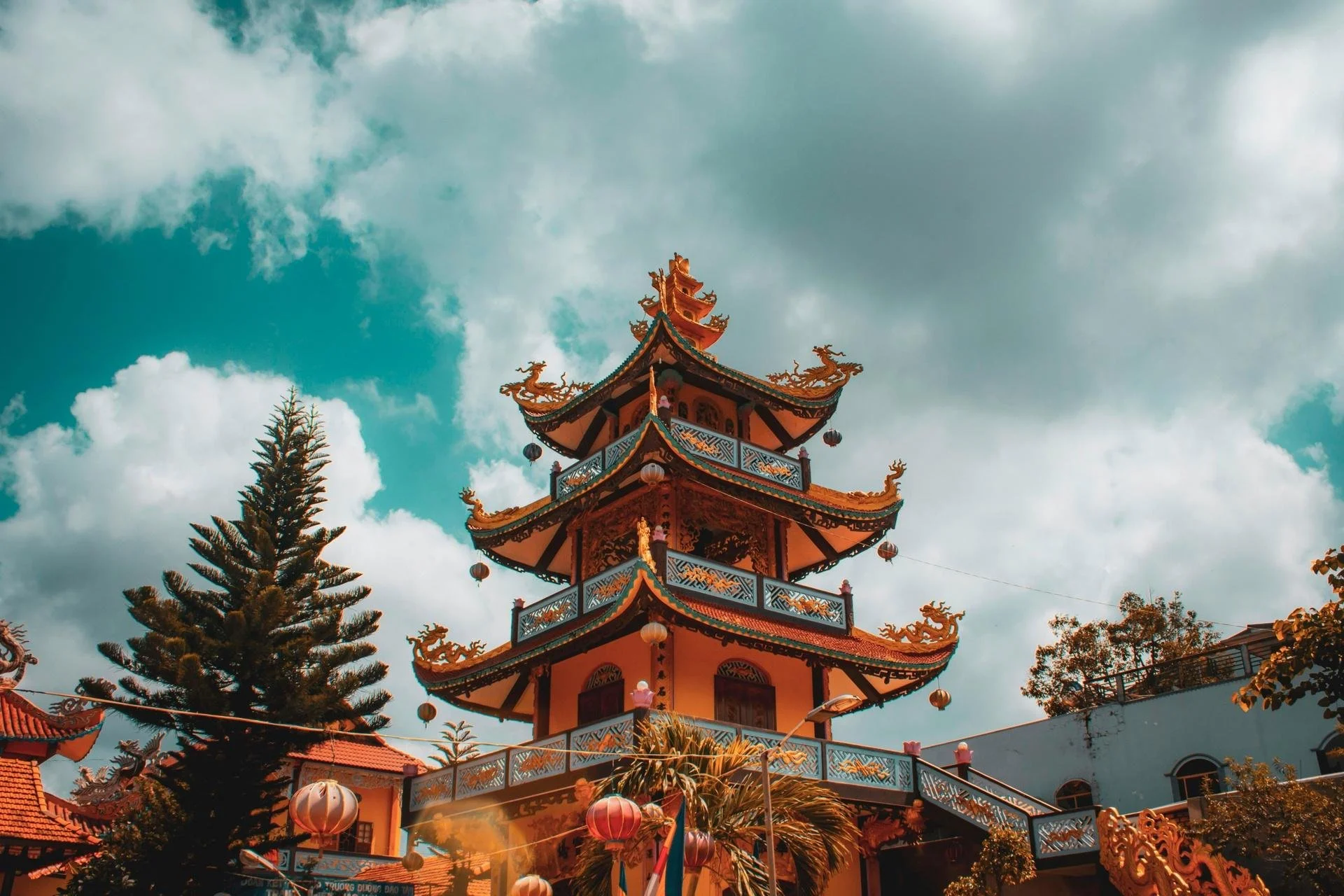 Multi-tiered Vietnamese pagoda tower with golden dragon sculptures and red lanterns in Hanoi