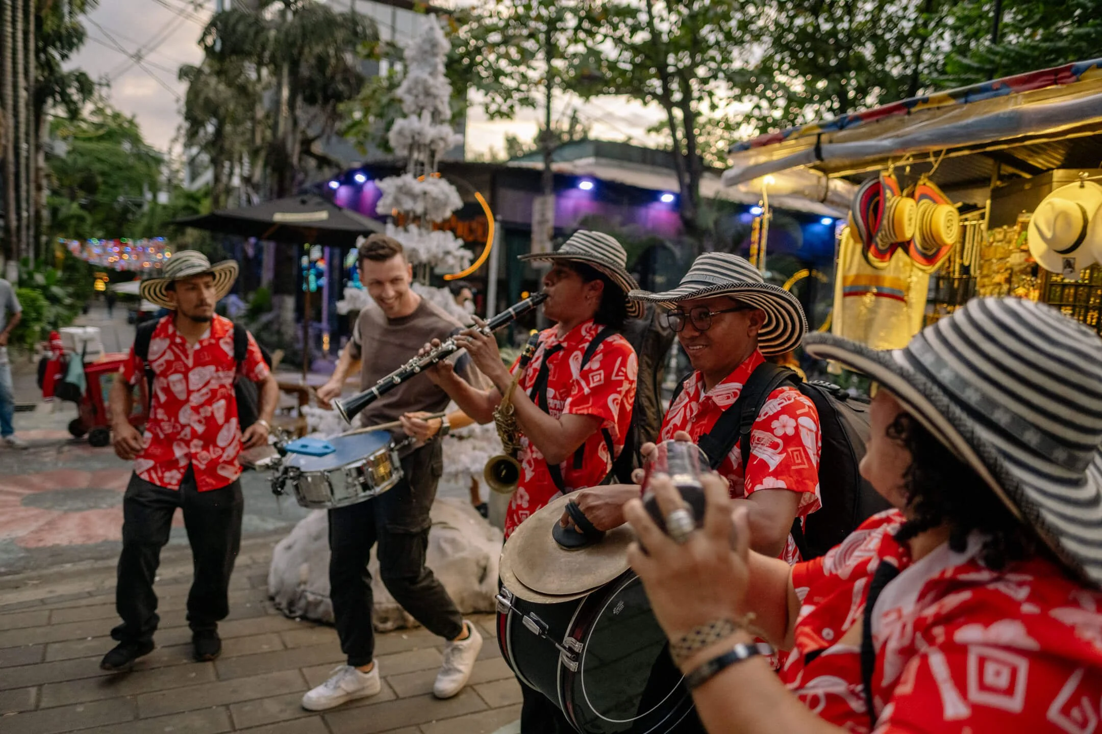 Street musicians in red shirts and sombrero vueltiao hats performing in a lively Medellín plaza.