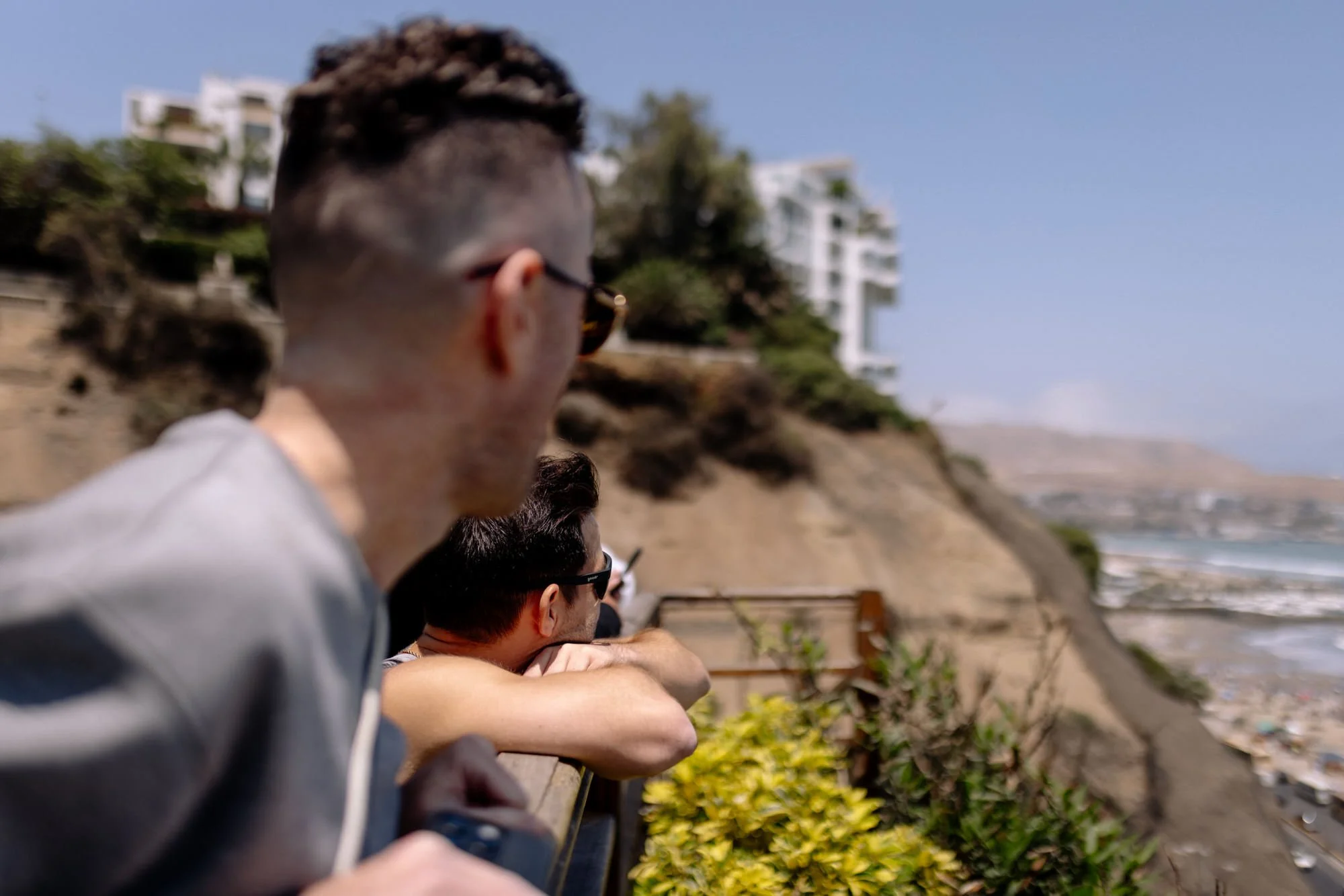 two guys look over the railing along the Malecon in Lima Peru at the pacific ocean