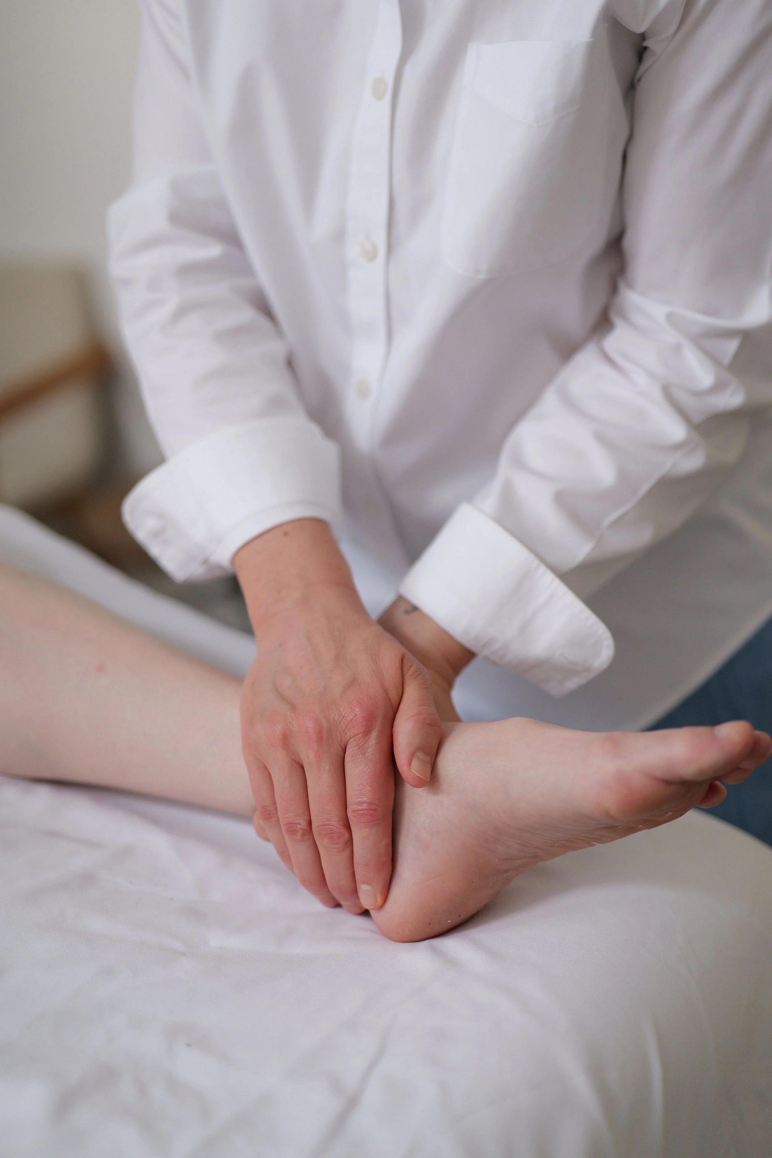 A reiki practitioner giving reiki to a patient's foot during a session.