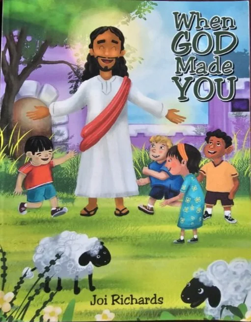 Children playing with a depiction of Jesus Christ in a colorful outdoor scene with trees, grass, flowers, and sheep. The book title is 'When God Made You' by Joi Richards.