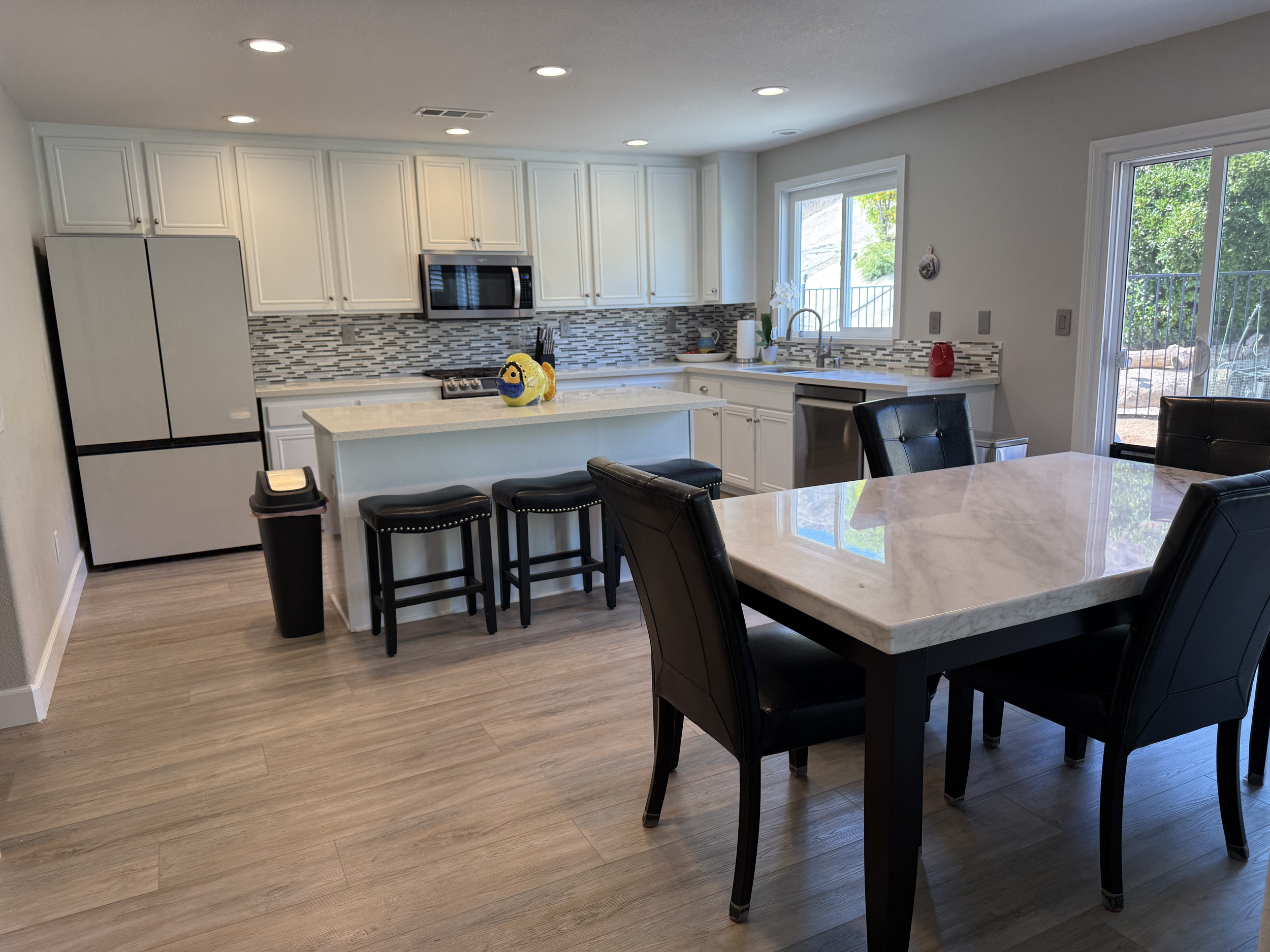 Castaic real estate listings in Los Angeles County: Modern kitchen with white cabinets, stainless steel appliances a sliding glass door leading to an outdoor area.