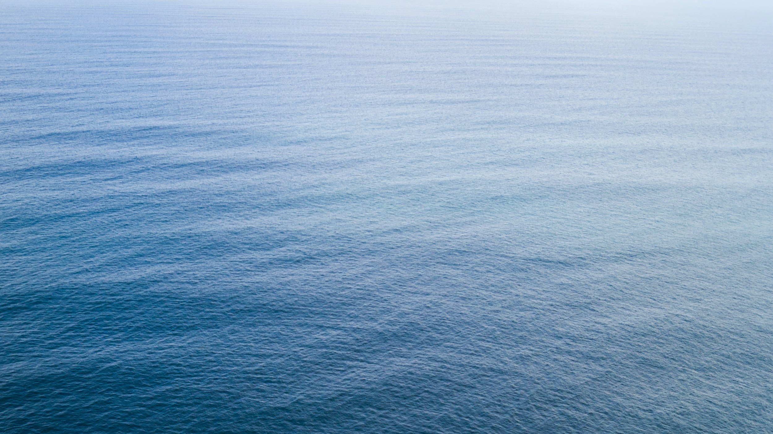 Overview of calm blue ocean water with gentle ripples under bright sky