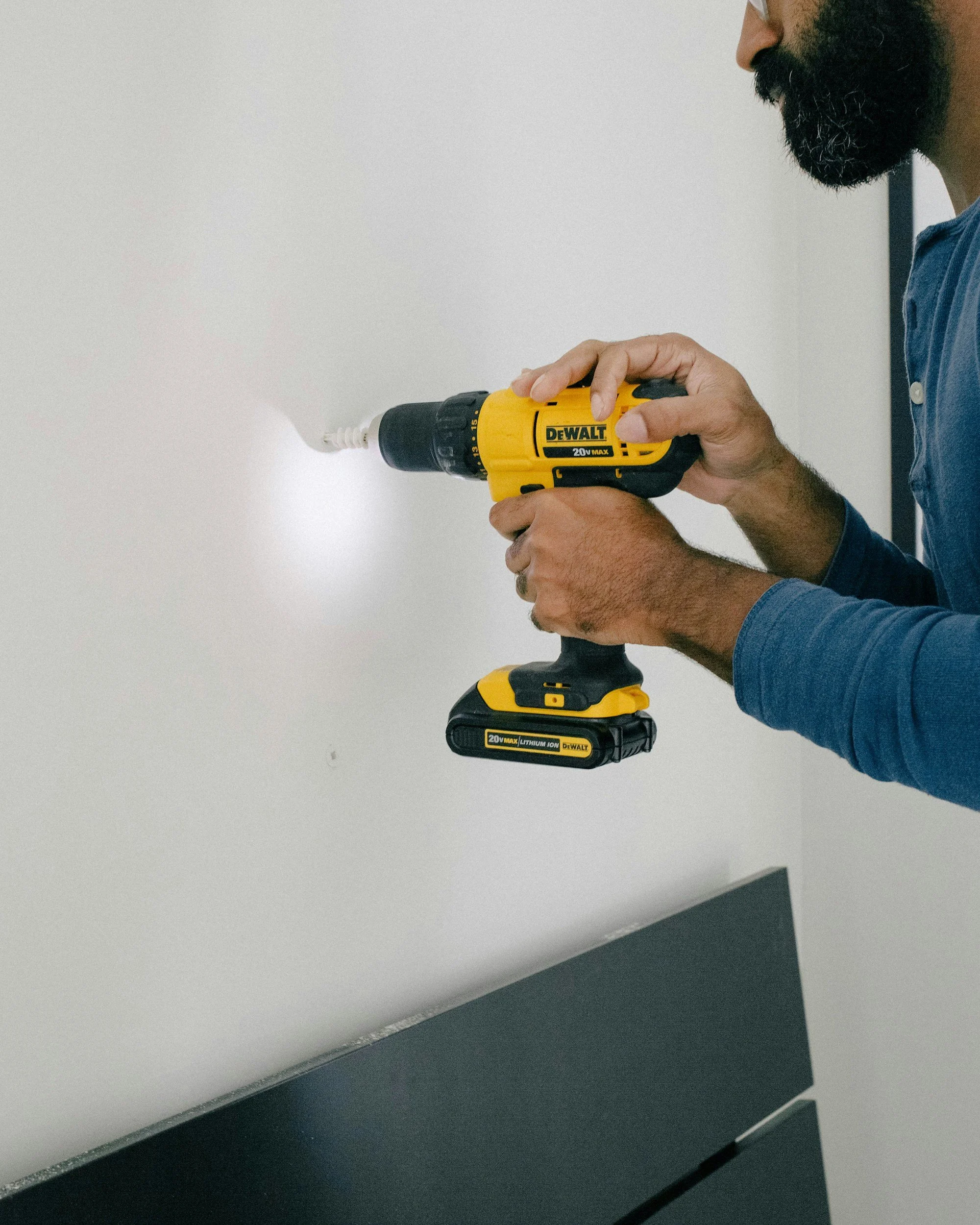 Man with a beard drilling a hole in a wall working on home improvement construction.