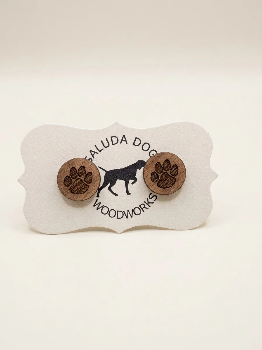 Round wooden stud earrings engraved with tiger paw prints on a Saluda Dog Woodworks card