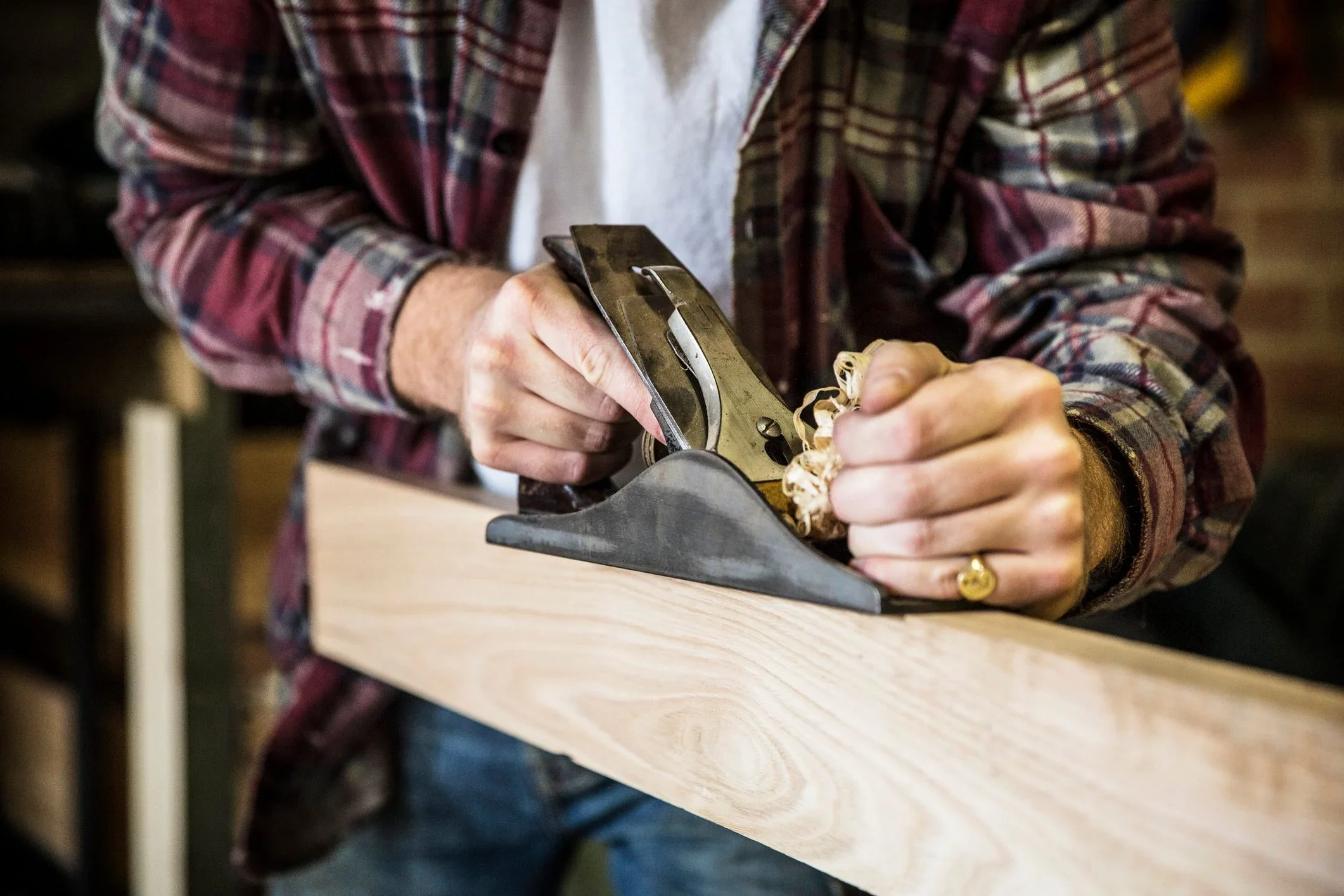 Woodworker smoothing a board with a hand plane in the shop