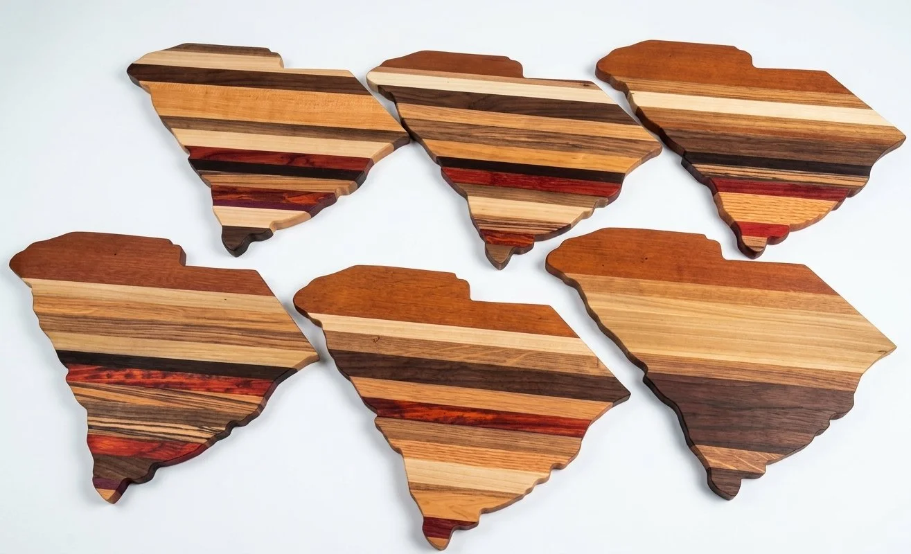 Six South Carolina-shaped cutting boards in striped mixed hardwoods by Saluda Dog Woodworks