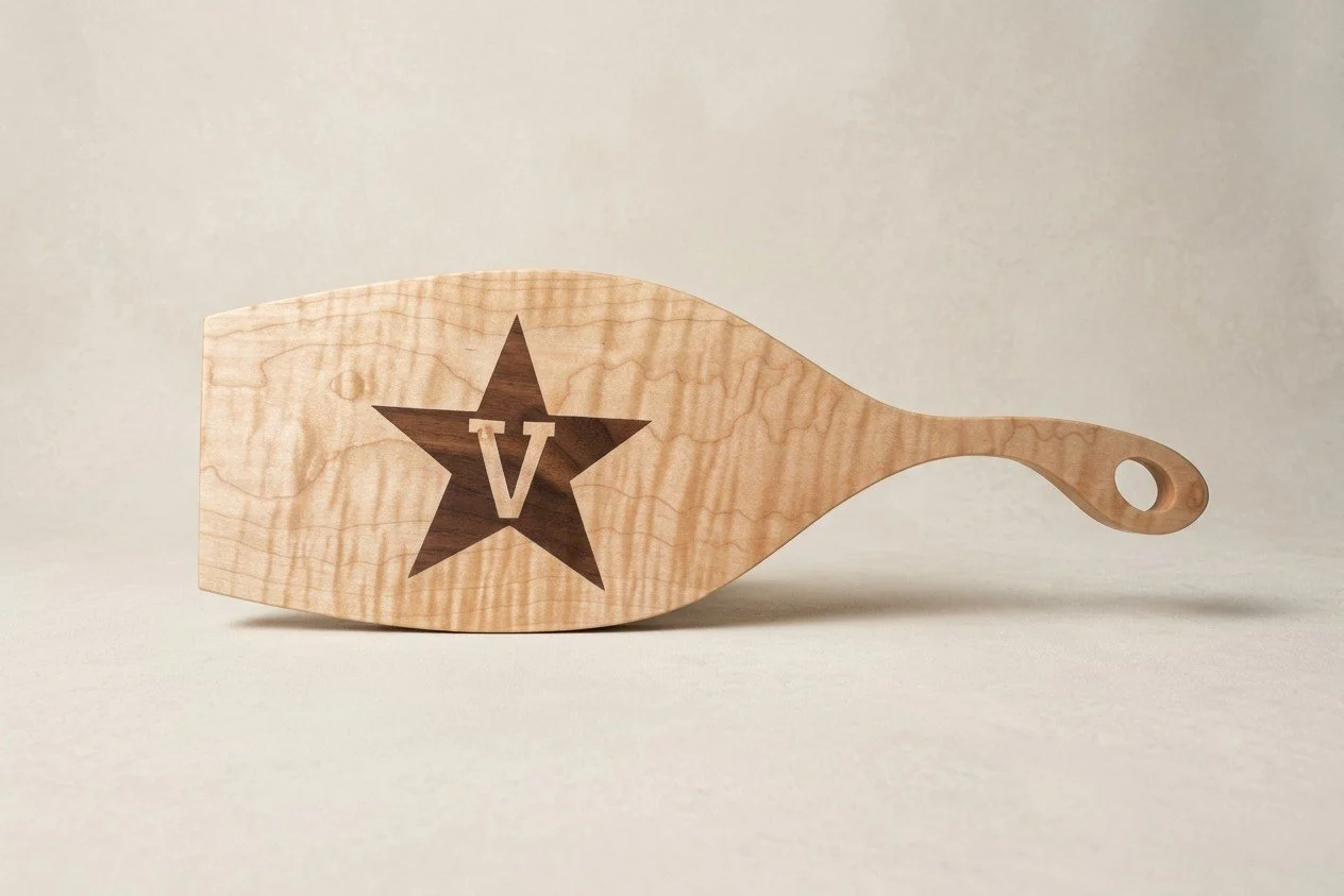 Curly maple serving paddle board with an inlaid Vanderbilt star V logo by Saluda Dog Woodworks