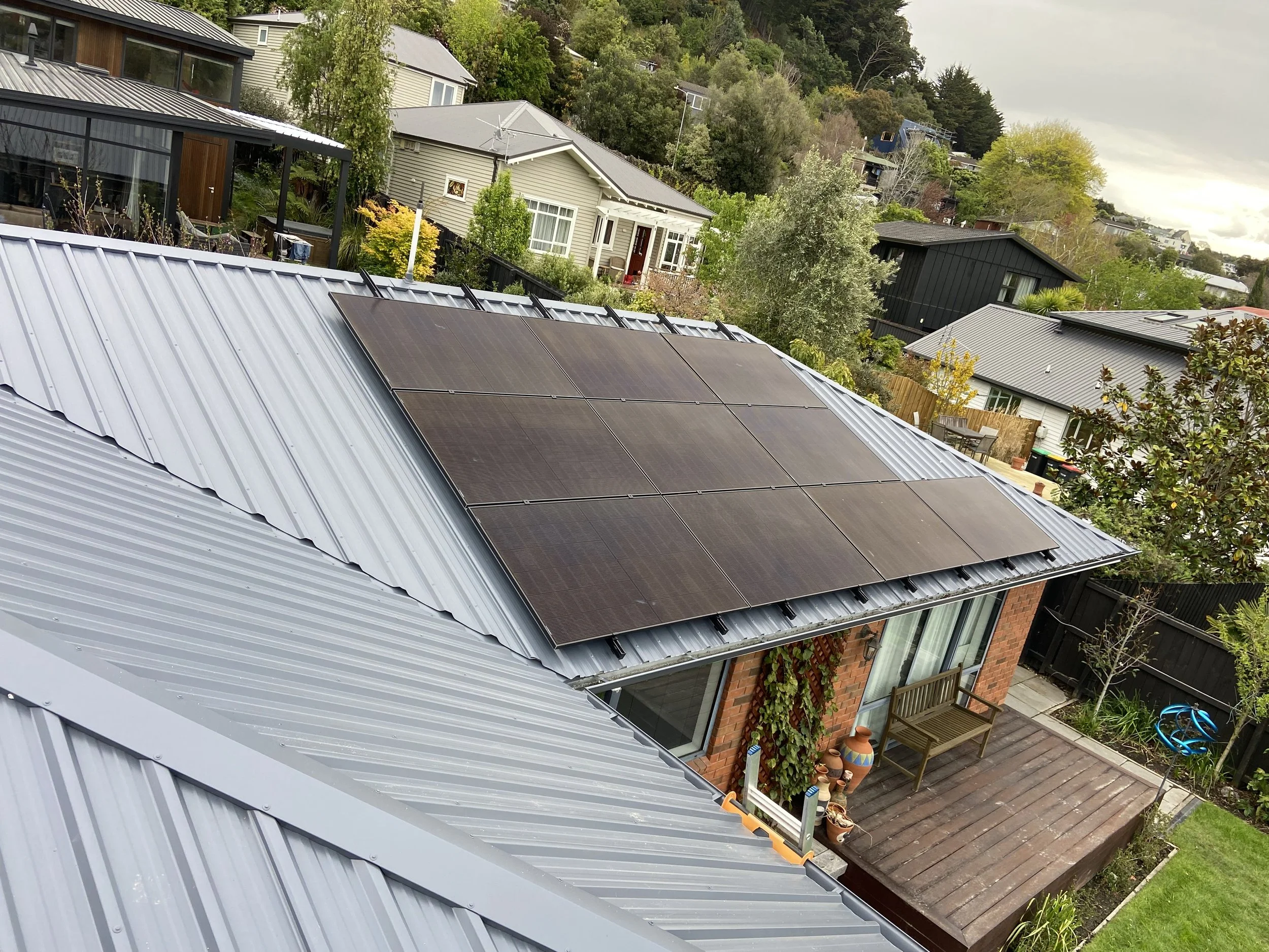 A house with solar panels installed on its metal roof in landscape.