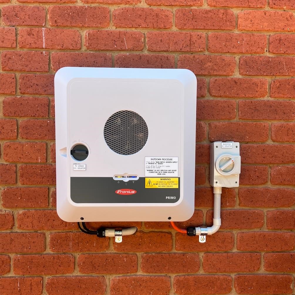 A Fronius GEN24 inverter installed at someone's house on a brick wall externally