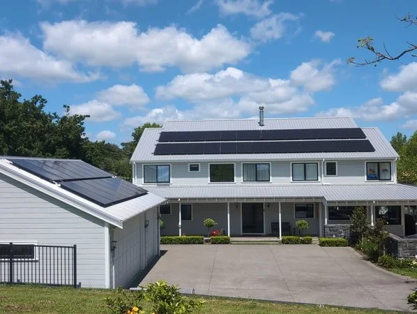 A two-story house adn detached garage with 40 modern, all-black solar panels on the roof.