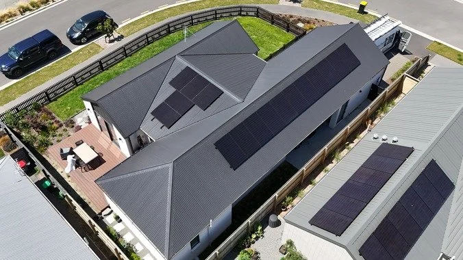 A house with solar panels installed on its metal roof in landscape.
