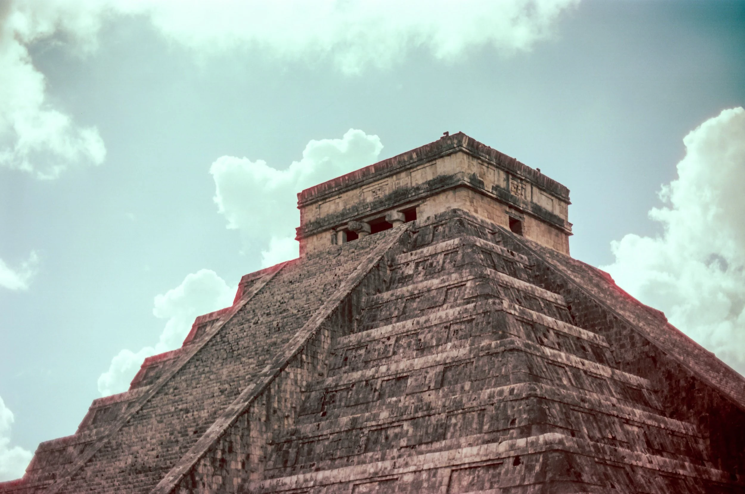 A close-up view of the ancient Mayan pyramid of El Castillo at Chichen Itza against a cloudy sky - Shot on 35mm film