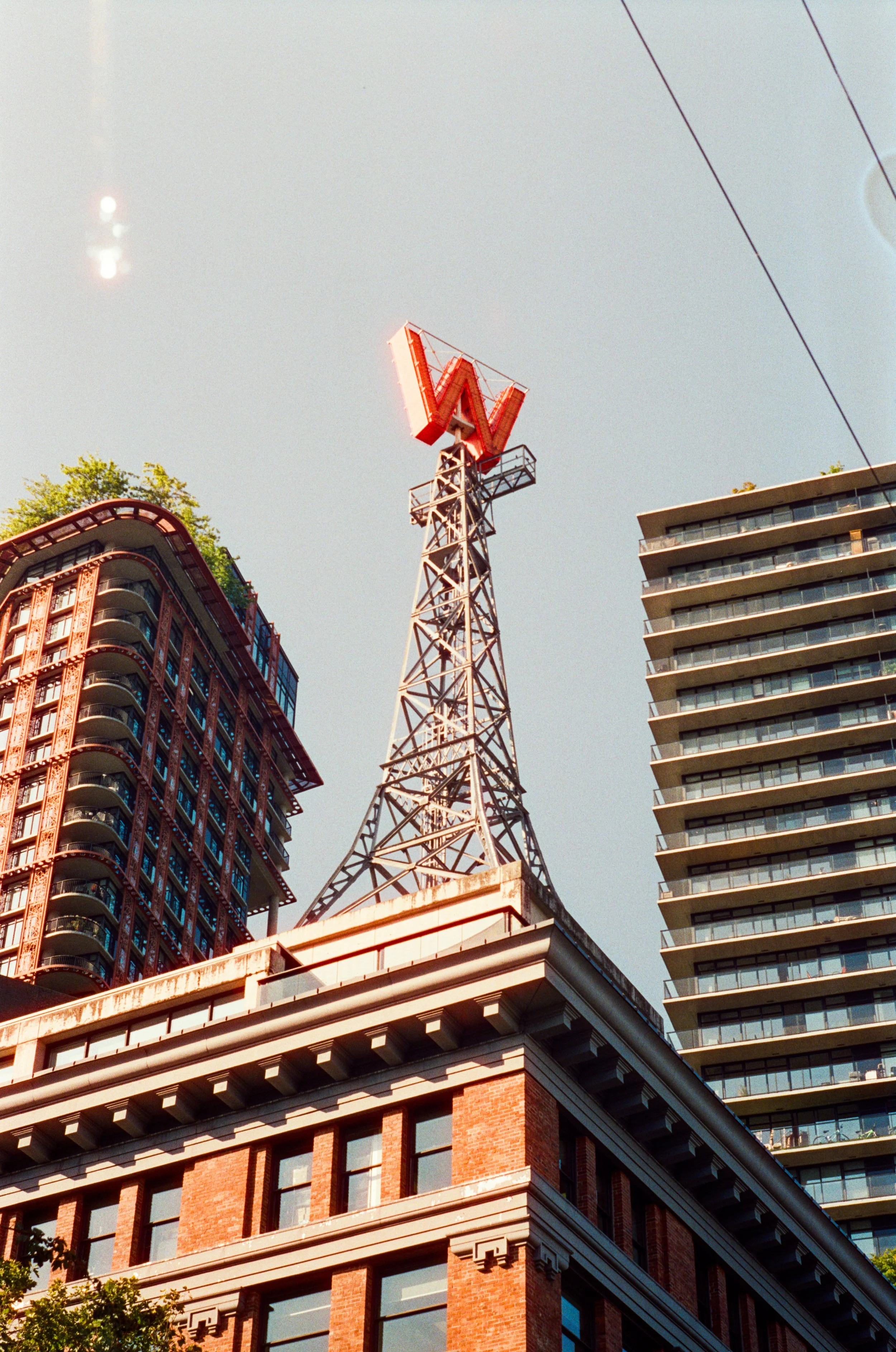 View of buildings with a prominent red 'W' sign on a tall metal tower against a clear sky.