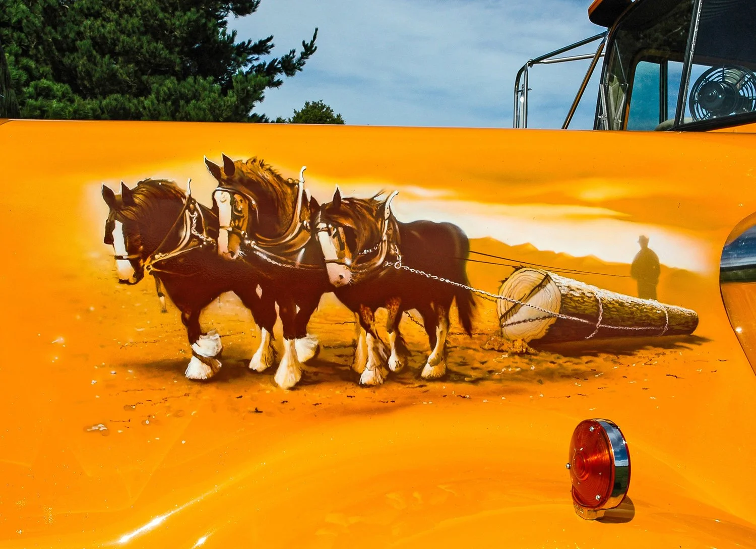 mural featuring horses and a log painted on the side of the bonnet of a yellow truck