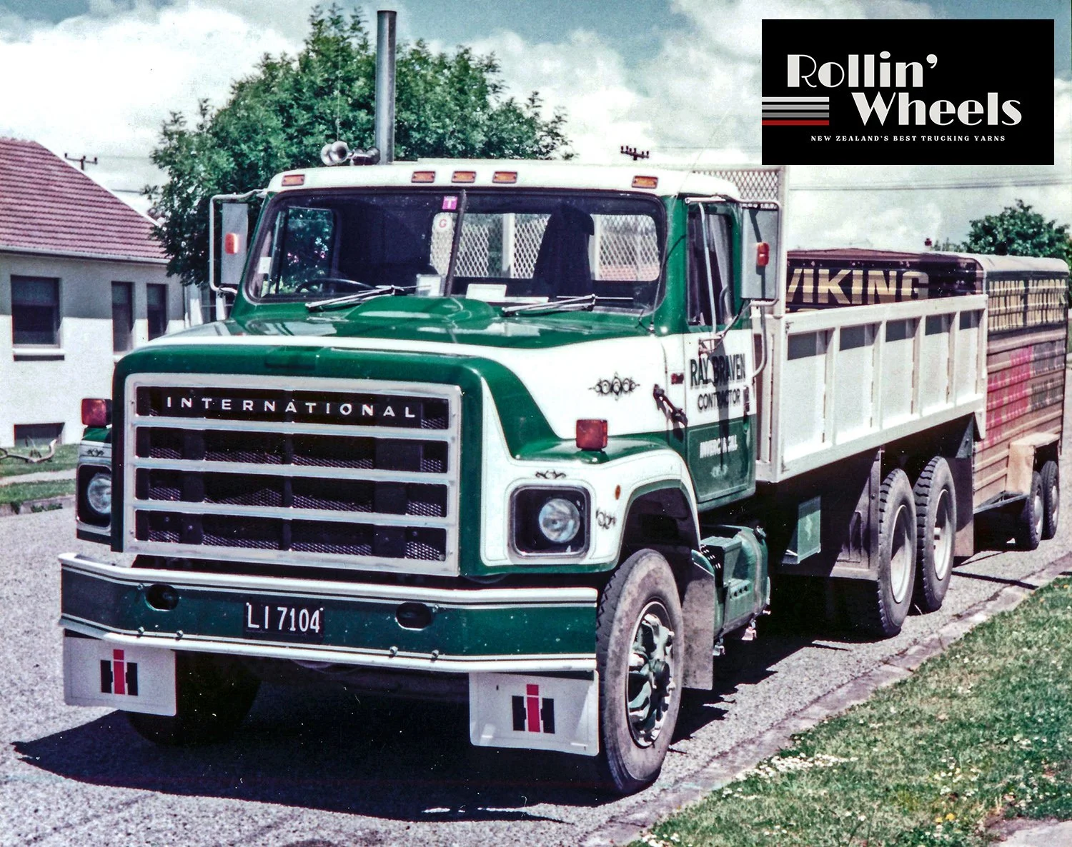 a white and green tip truck parked on the side of a road with houses in the background