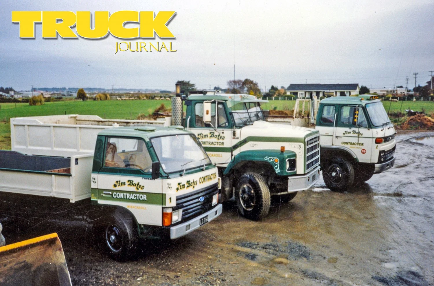 three white and green trucks parked in a shingle yard with fields and a house in the background