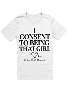 White T-shirt with black text that says 'I CONSENT TO BEING THAT GIRL' and smaller text below that reads 'The fashion school ... appreciated' with a small heart graphic.