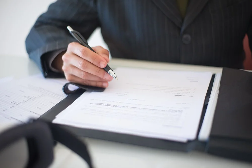close up of hand signing printed business document