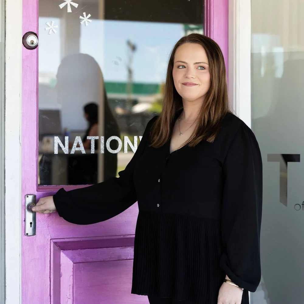 kim standing by mrs tradie christchurch entrance with hand on door smiling