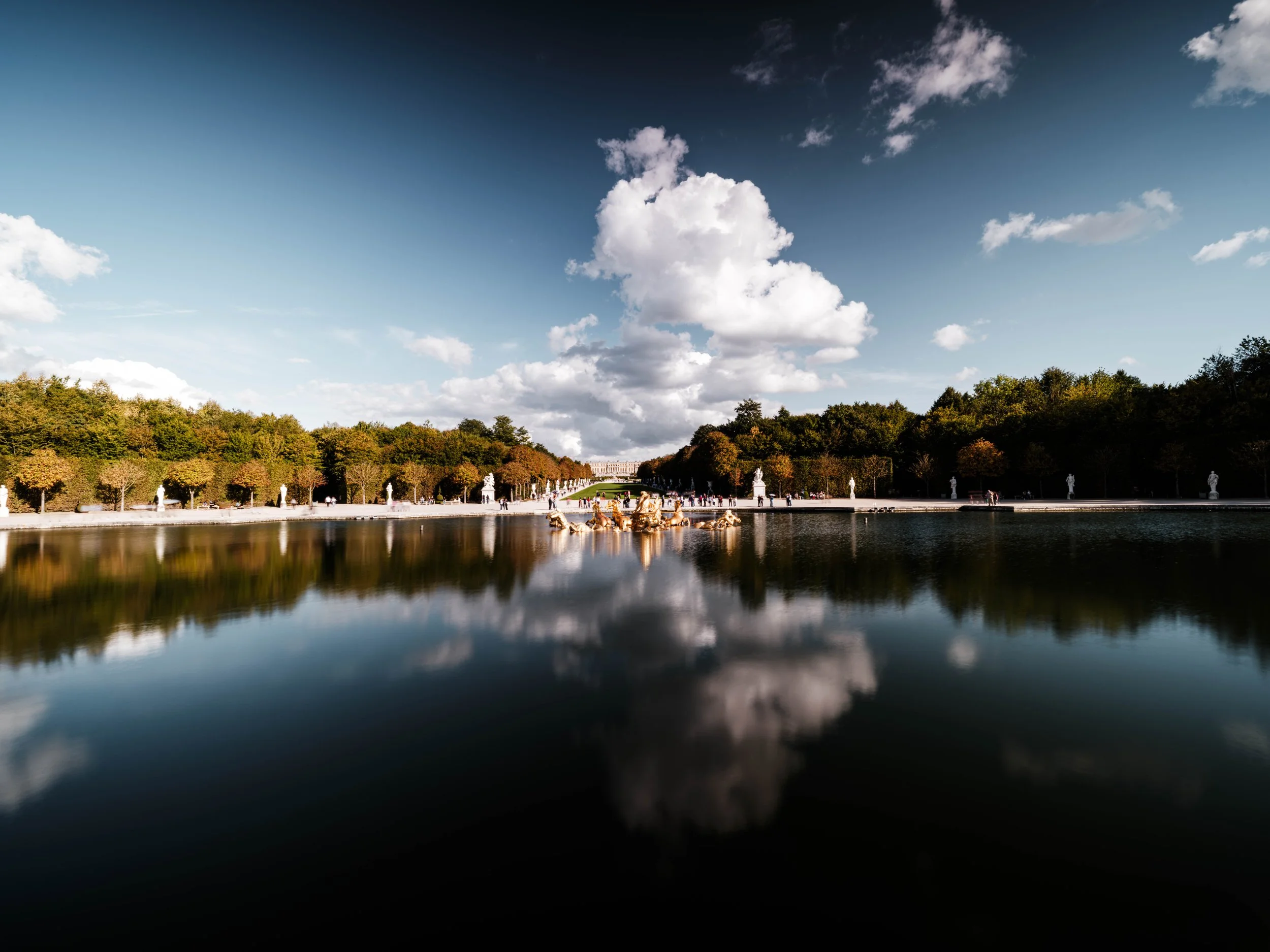 A calm basin reflecting sky and trees, where symmetry turns a fleeting afternoon into a moment of quiet balance.