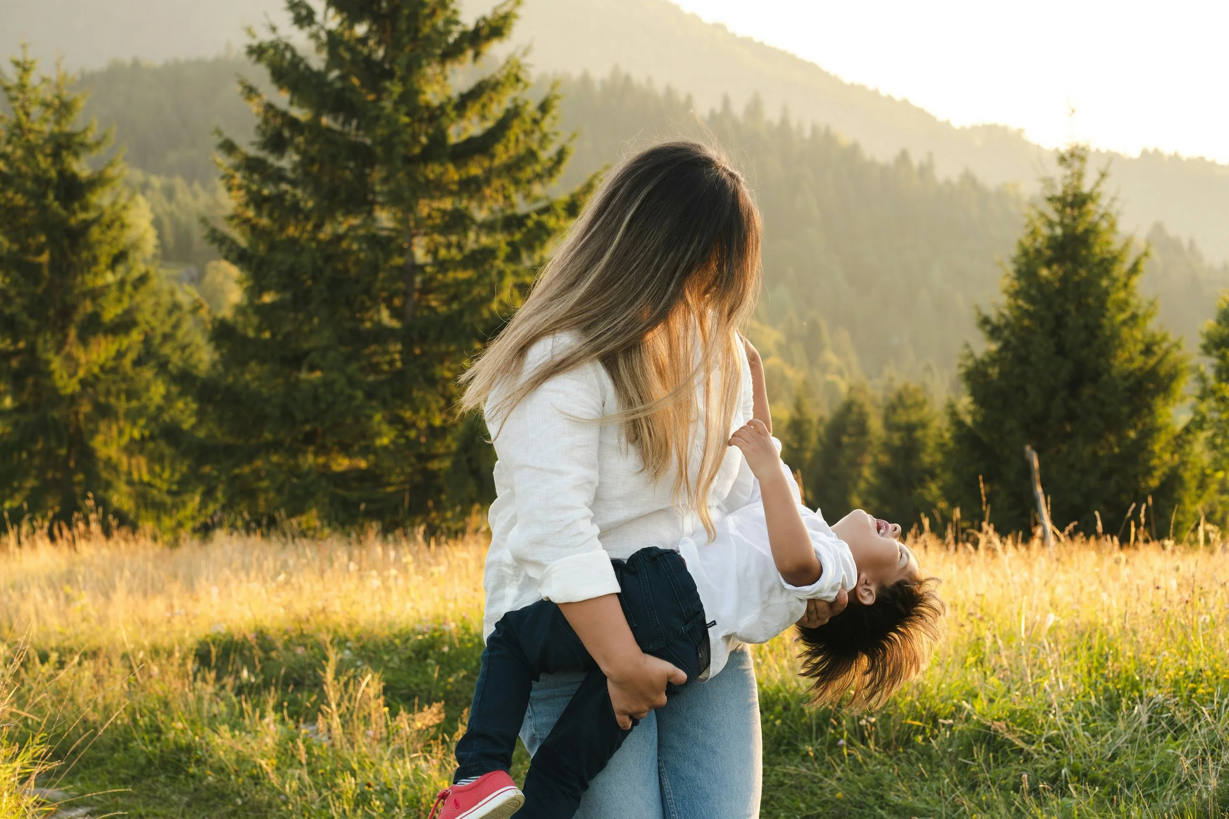 Mother and child playing in a sunlit field.