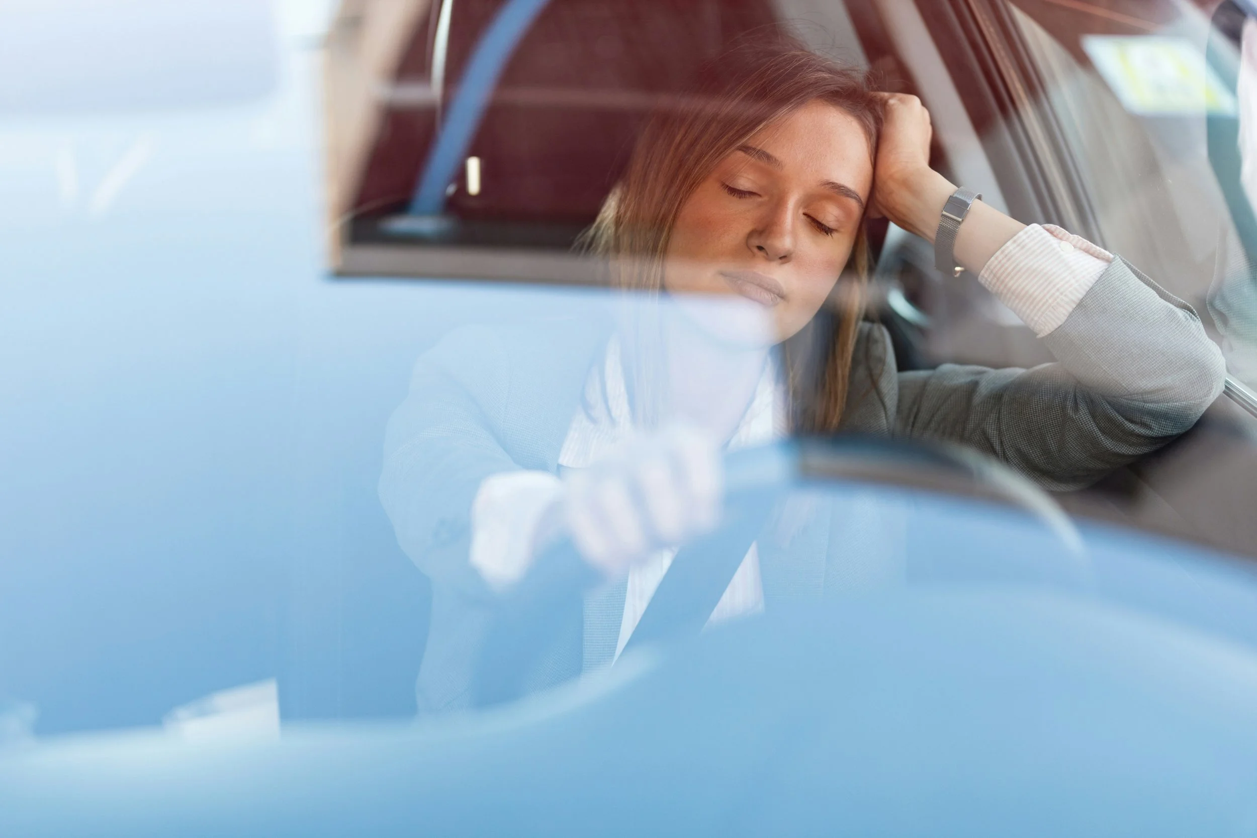 Working mom in a blazer sitting in her parked car with her eyes closed before school pickup