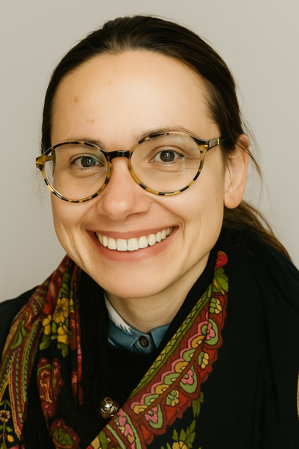 Radmila Gurkovsky, LCAT, licensed creative arts therapist at Overture Therapy, smiling in round glasses and a patterned scarf