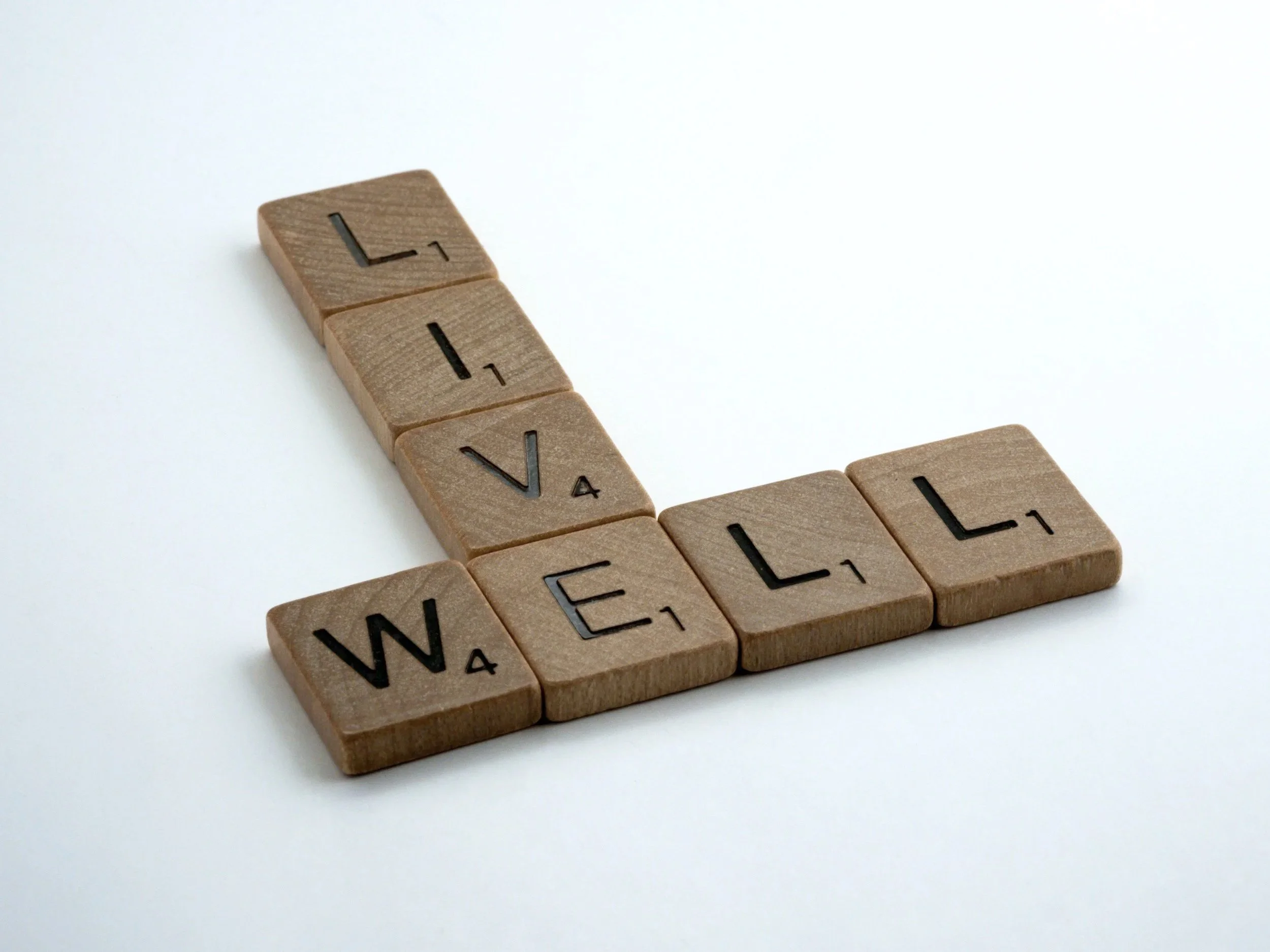 Scrabble tiles spelling out 'I WILL' arranged in a 'L' shape on a white surface.