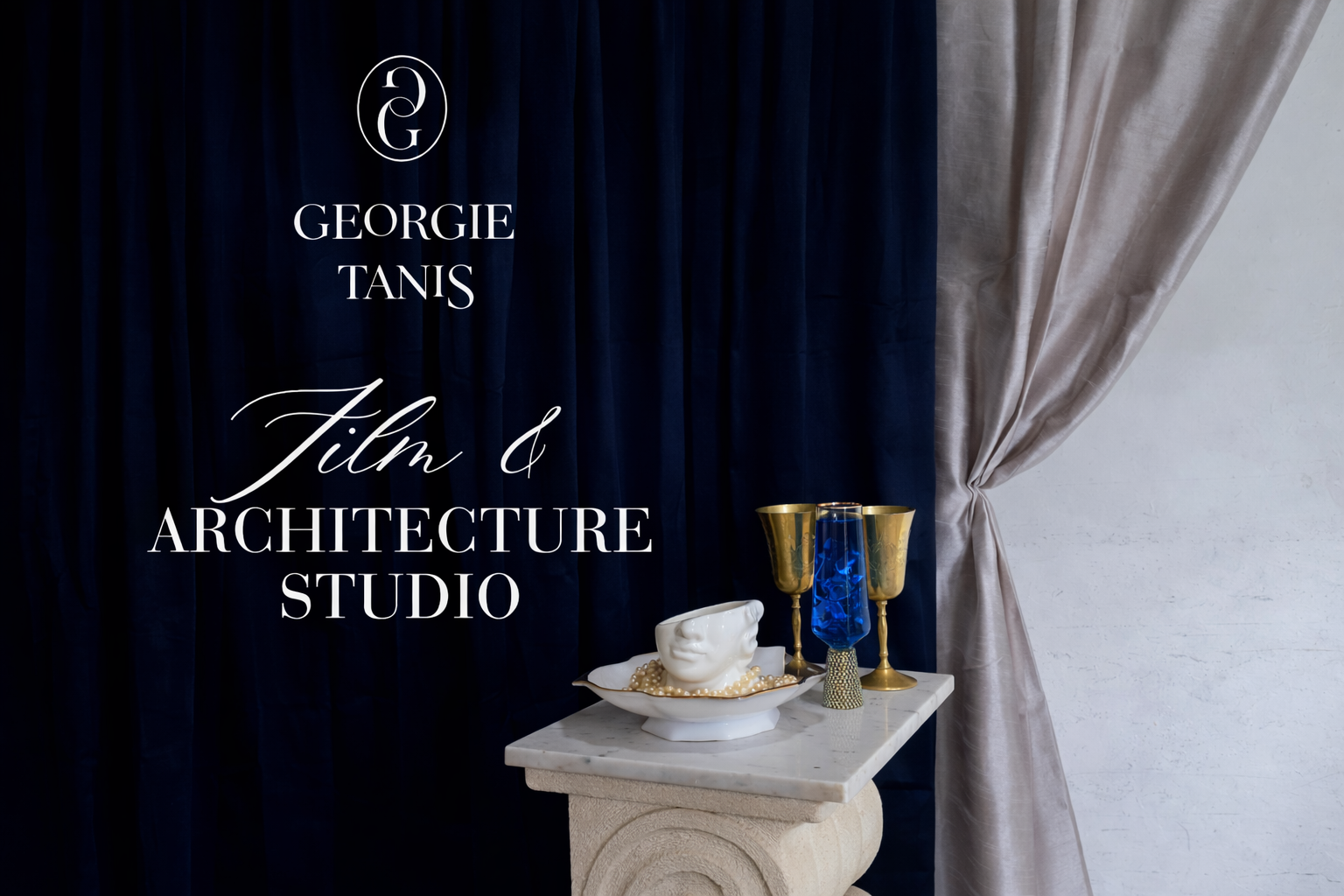 Text overlay with the words 'Georgie Tanis Film & Architecture Studio' on a background with dark blue curtains and a marble pedestal holding decorative objects including a ceramic face, gold and blue cups, and a patterned vase.
